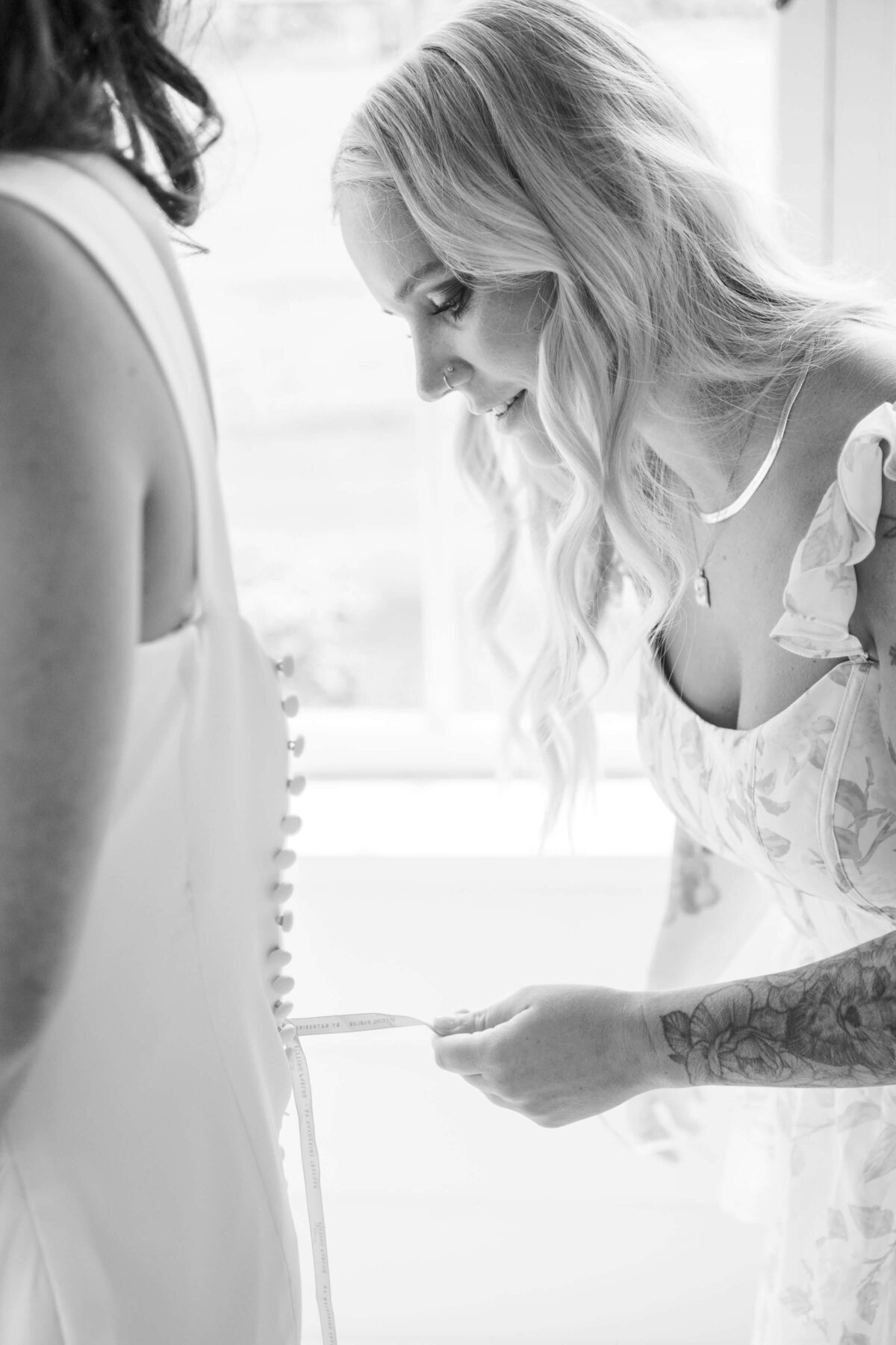 A bride getting her dress laced up, representing the little moments she and her bridal party enjoy together.