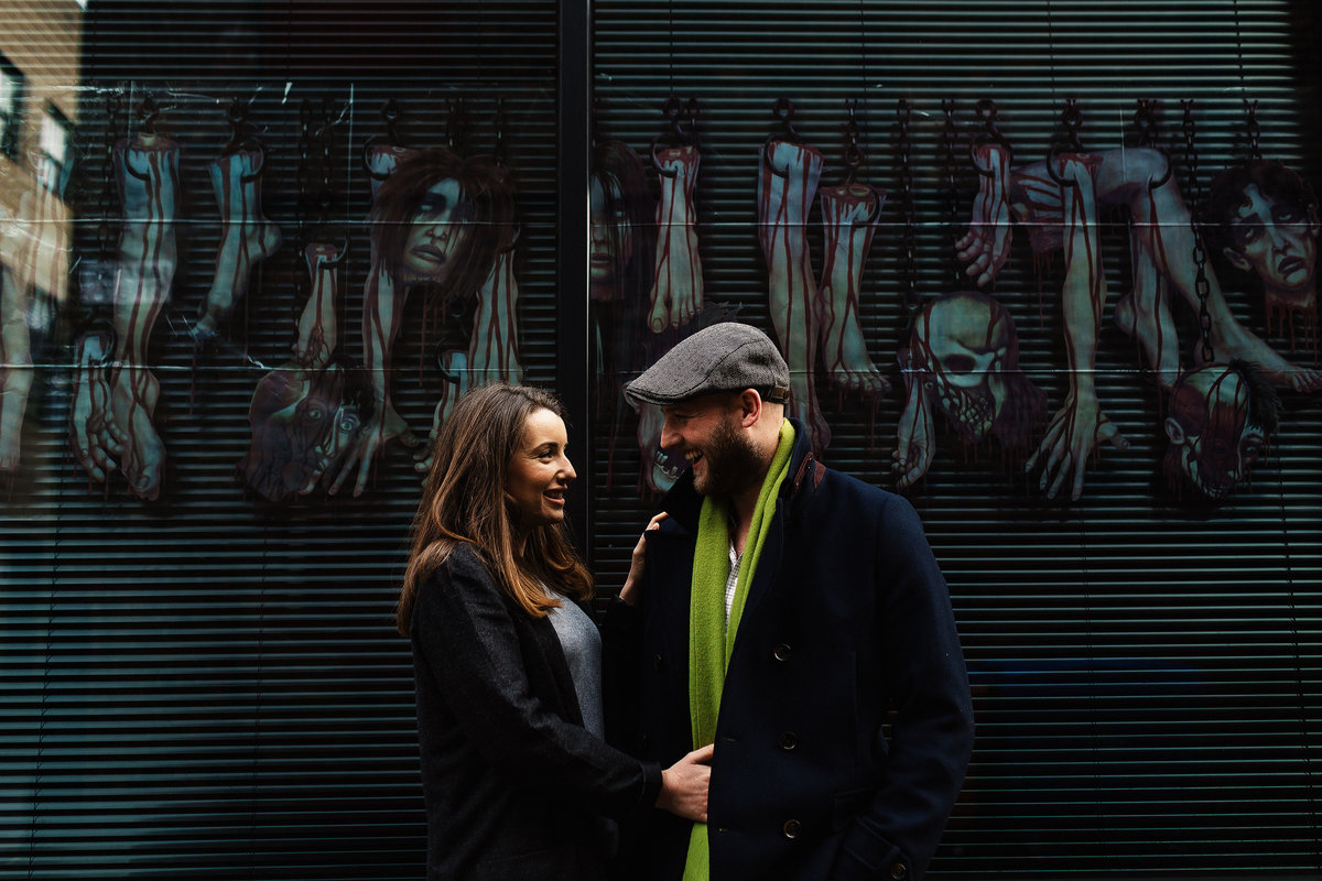 A pre wedding photograph of a couple stood in front of street art in Manchester Northern Quarter