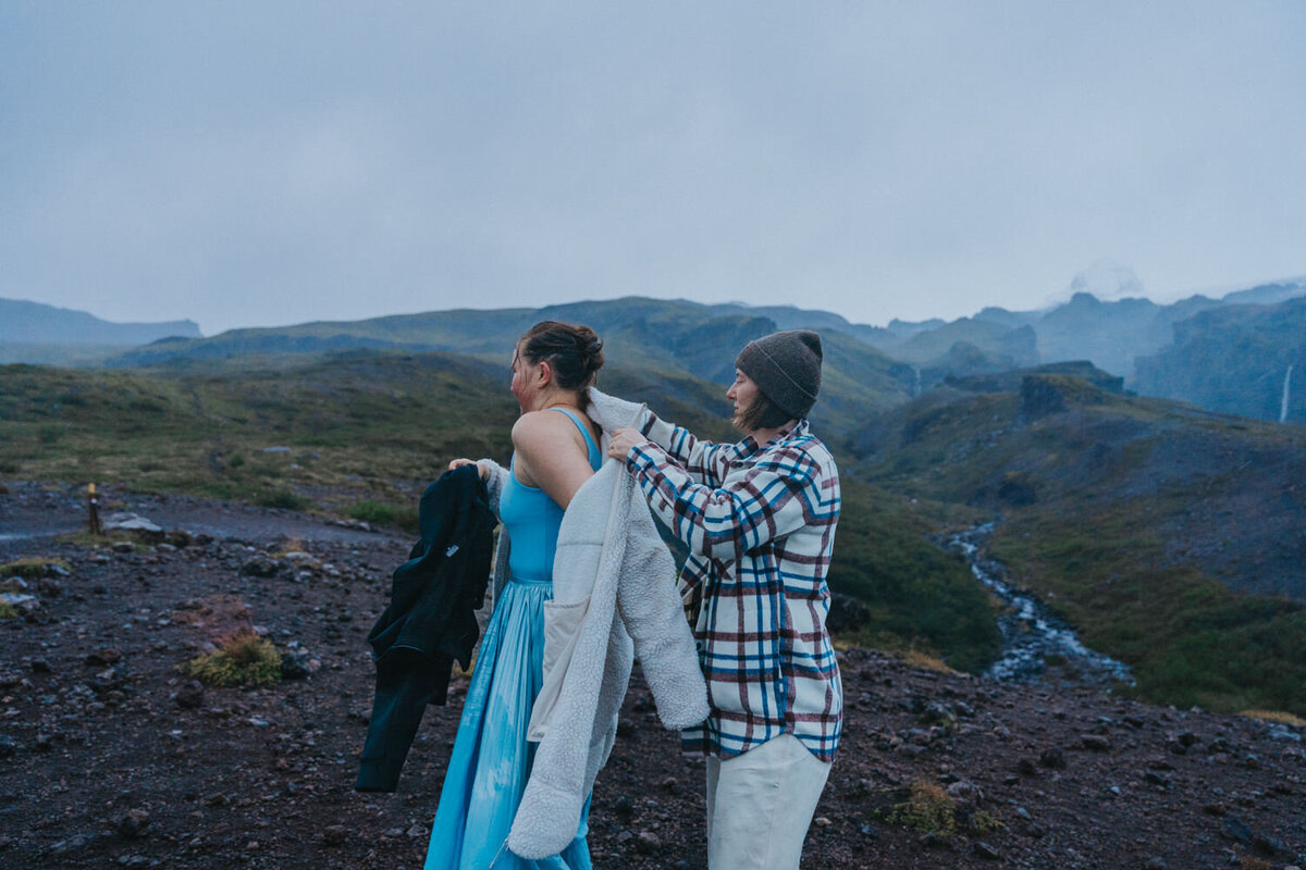 Wife helps her wife put on her coat 