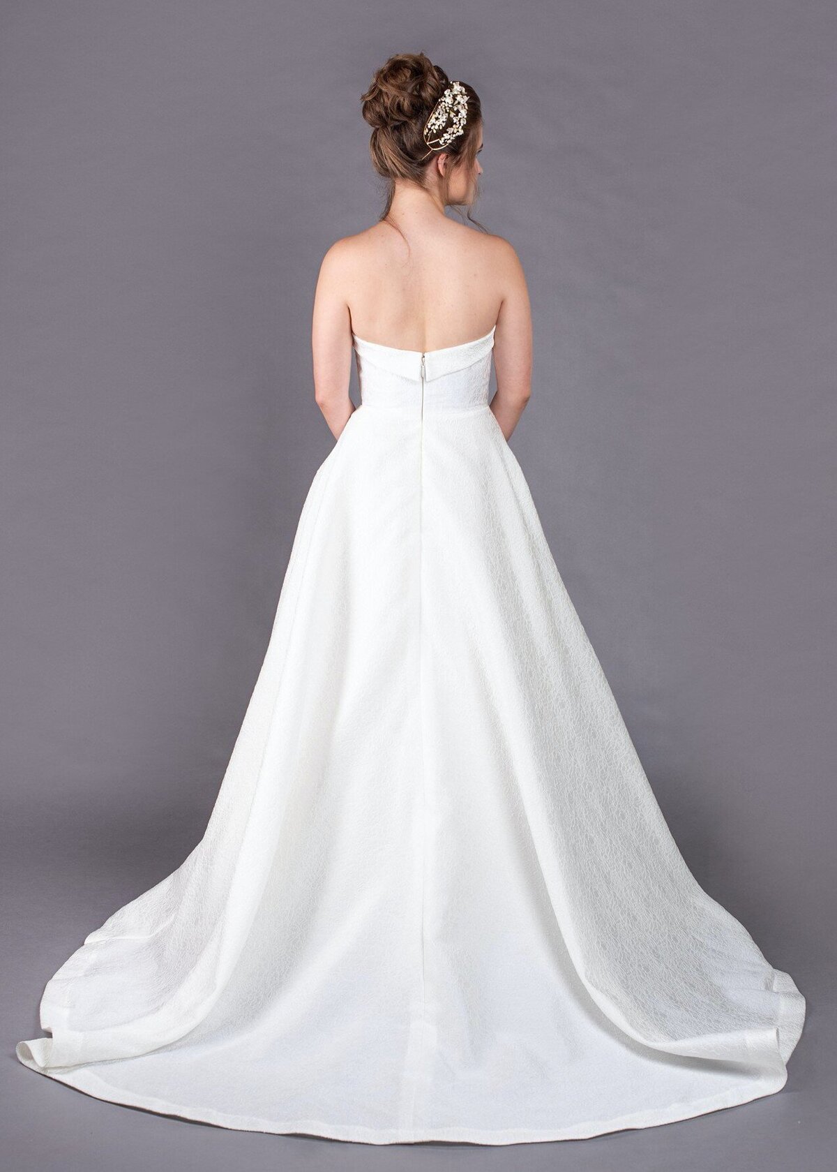 The back of the textured wedding dress is simple with its strapless neckline and shorter train.