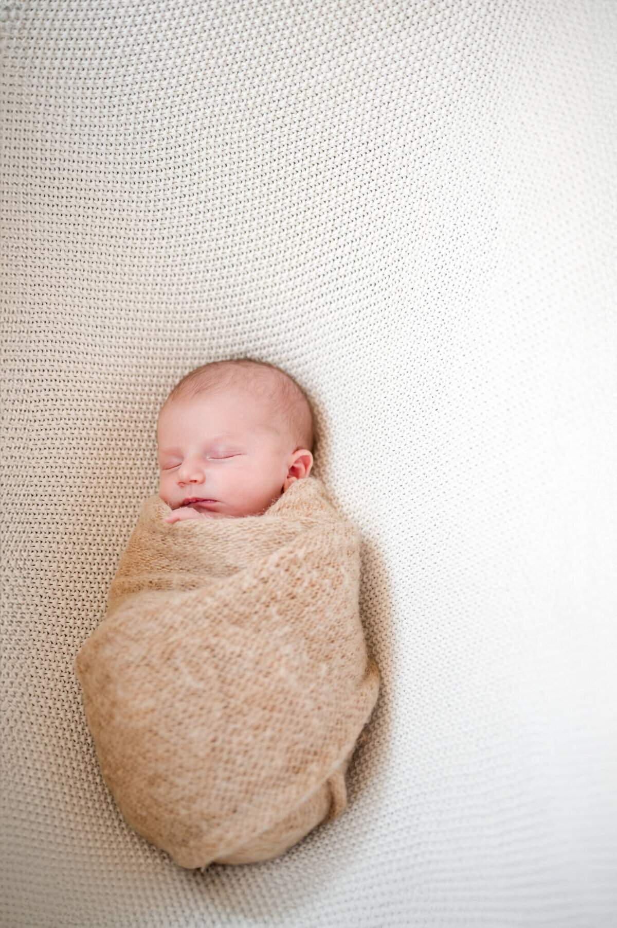 swaddled newborn on neutral blanket