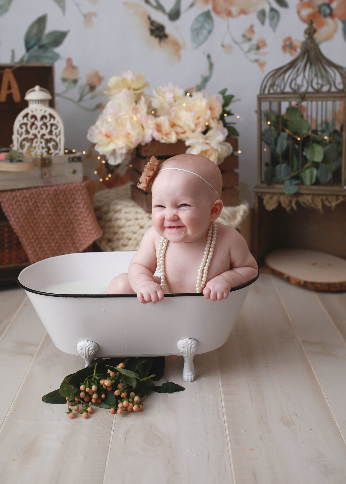 baby girl wearing pearls in white claw foot tub