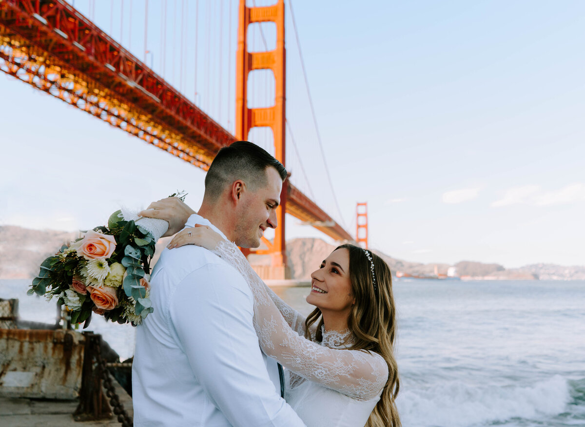 bride and groom post in front of golden gate bridge