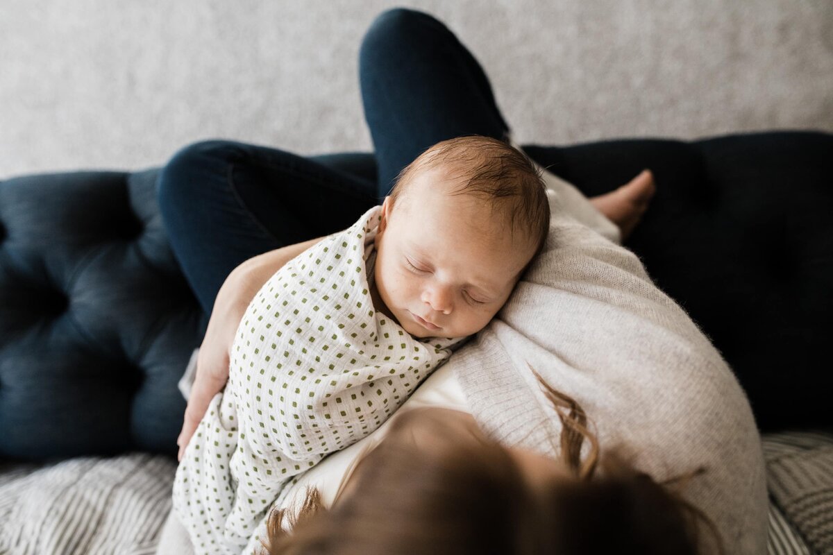 Newborn baby sleeping peacefully on a parent's chest during an in-home photography session.