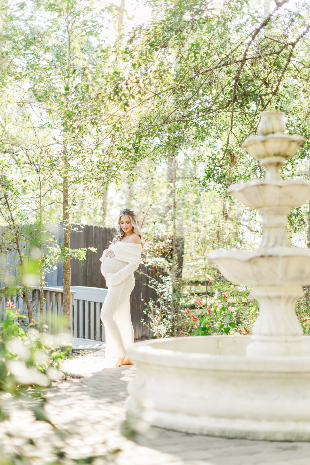 mom stands near outdoor fountain for maternity photo session