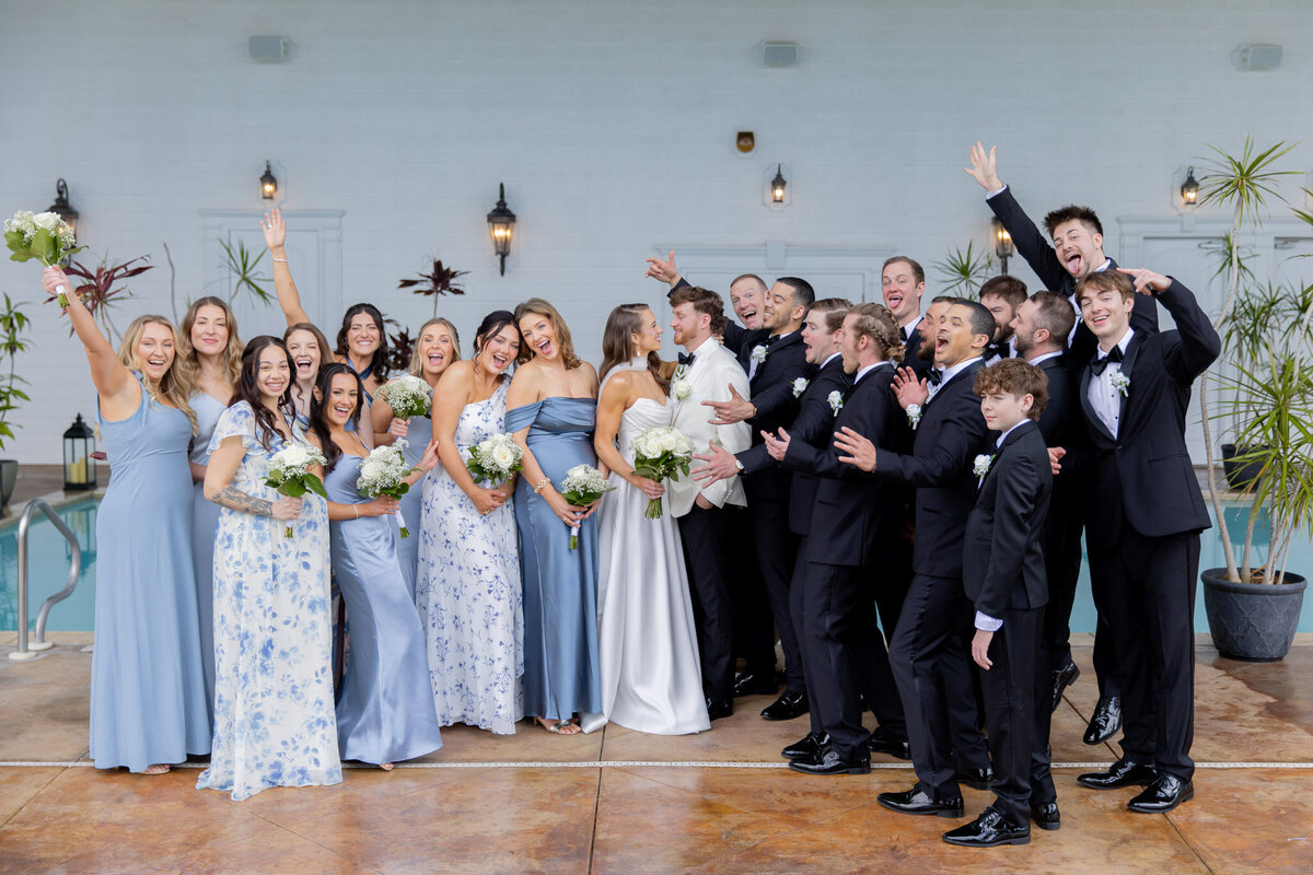 A bride and groom look into each other's eyes as their bridesmaids and groomsmen surround them celebrating.