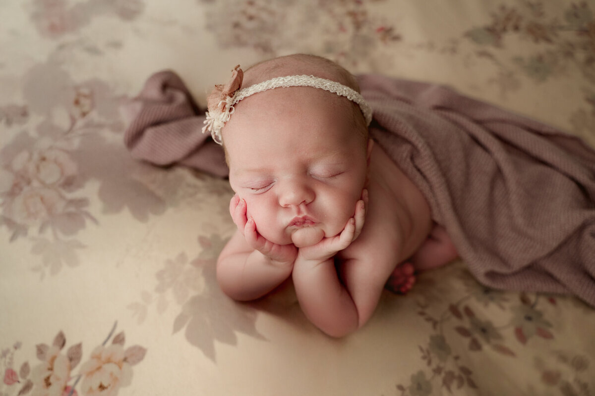 Dothan AL Newborn Photos; baby girl in the froggy, chin on hands position with floral fabric backdrop