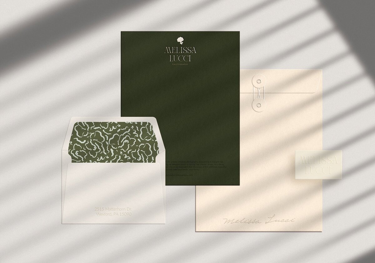 Three stationery items: a dark green letterhead, a beige envelope with a green-patterned interior, and a beige document folder with a button tie. All branding reflects Melissa Lucci's impeccable taste in design, perfect for showcasing her brand strategy consulting.