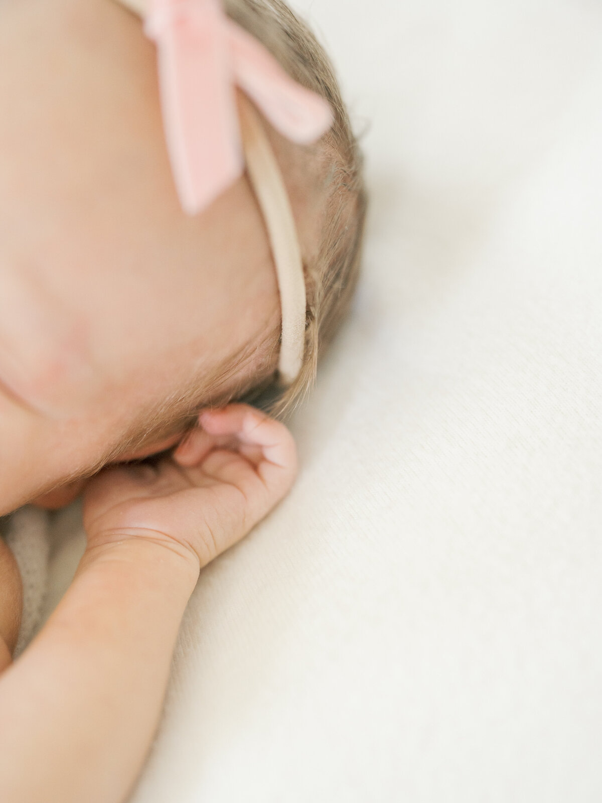 Newborn Baby girl fingers and hair wrapped in a pink bow in Williamsburg Virginia