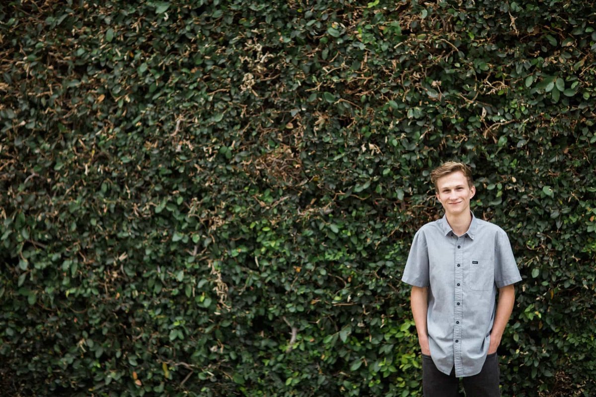 High School senior poses for photos in front of a wall of ivy
