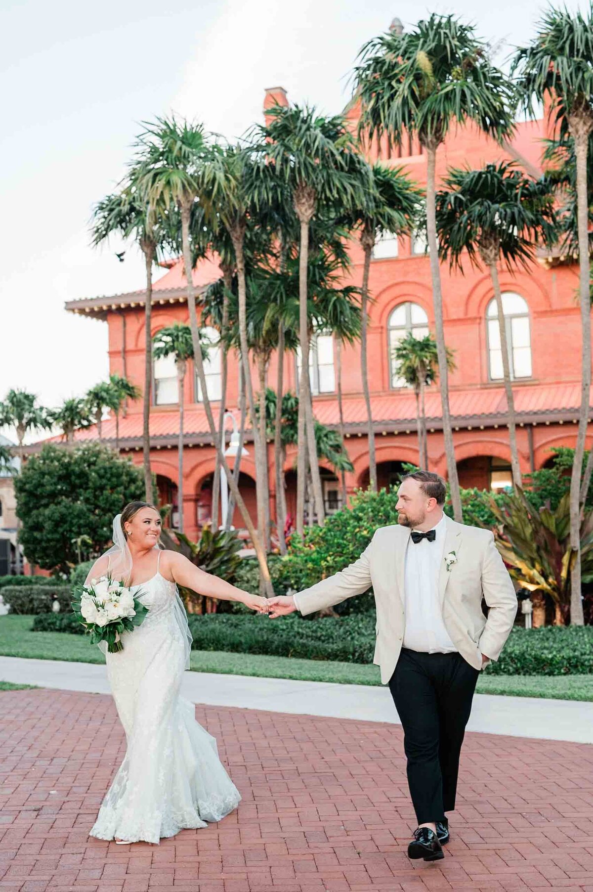 Bride and groom hold hands in front of the Customs House at their Key West wedding