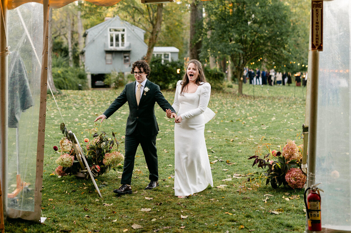 Bride gasping with hand on chest hand in hand with groom