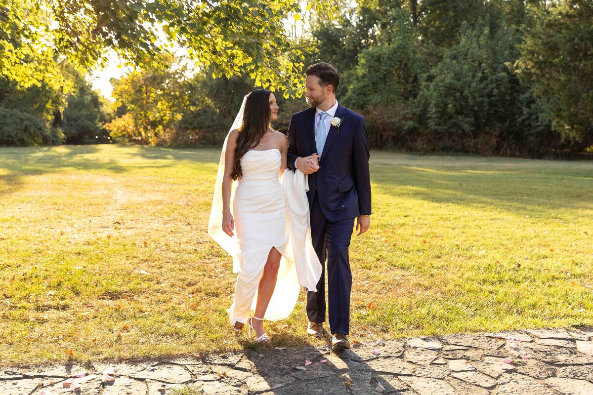Bride and groom holding hands while walking and looking at each other
