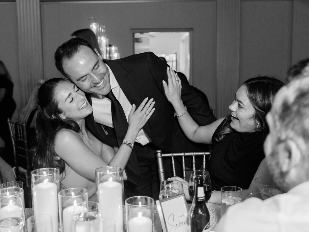An amusing interaction at a wedding, showcasing the joy between friends as they share laughter and connect, embodying warmth and happiness during a special occasion.