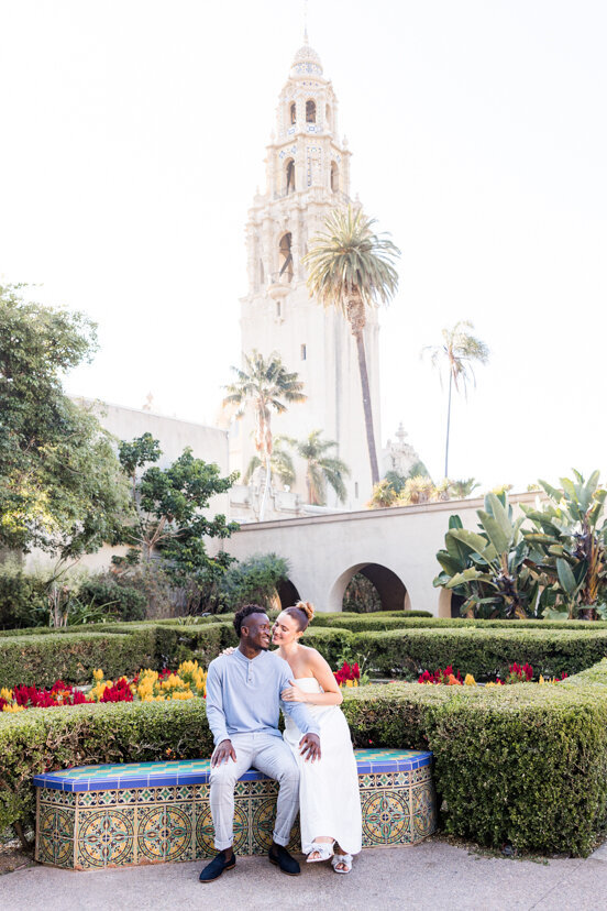 engaged-couple-sitting-in-Alcazar-Gardens-balboa-park-san-diego