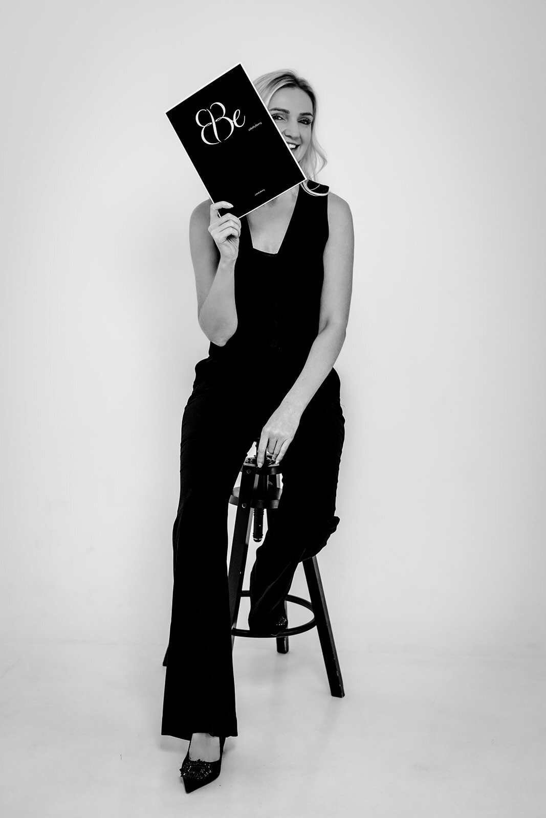 Black and white image of a women sat on a chair holding a piece of paper