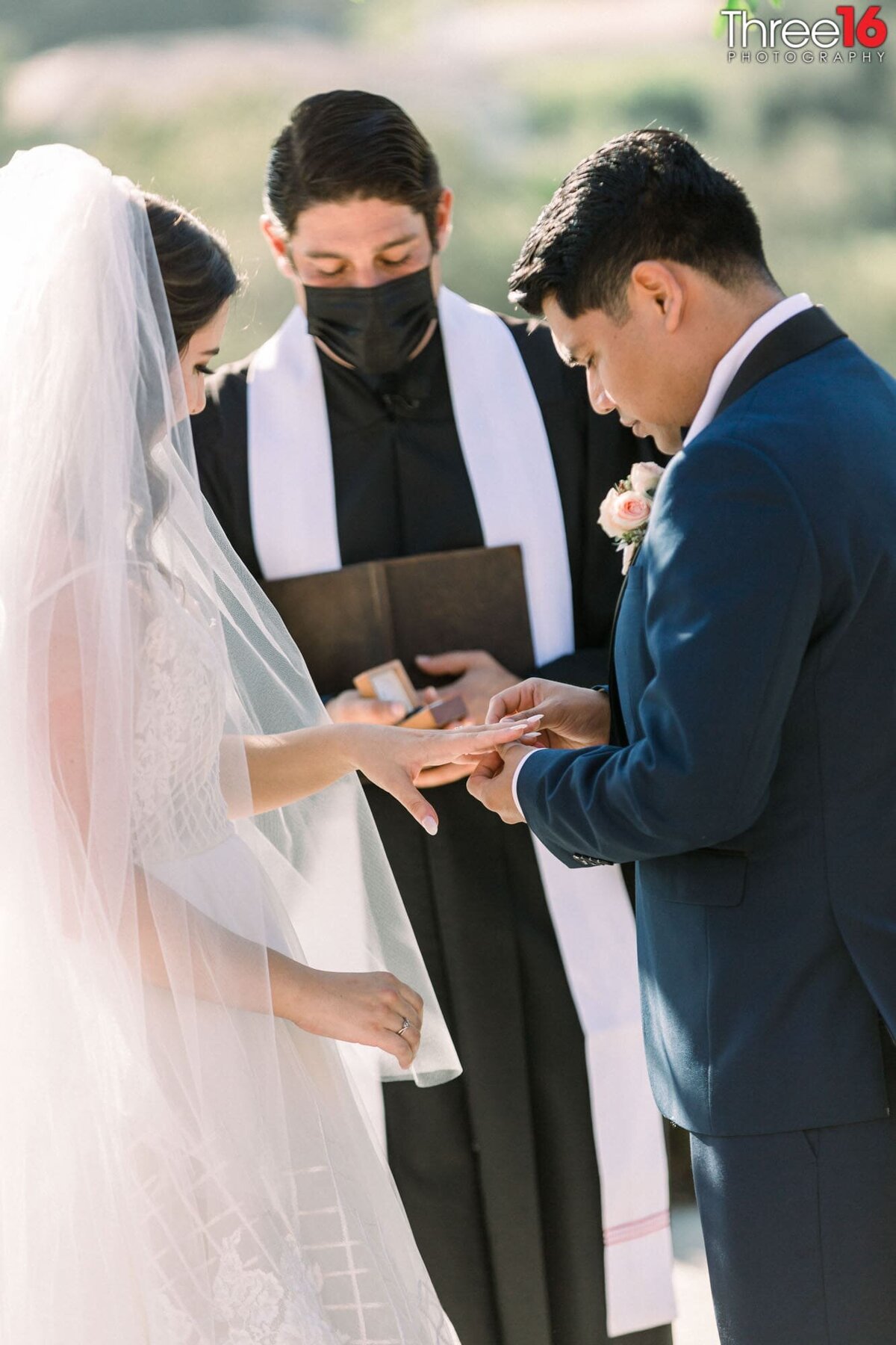 Groom slides the wedding ring on this Bride's finger