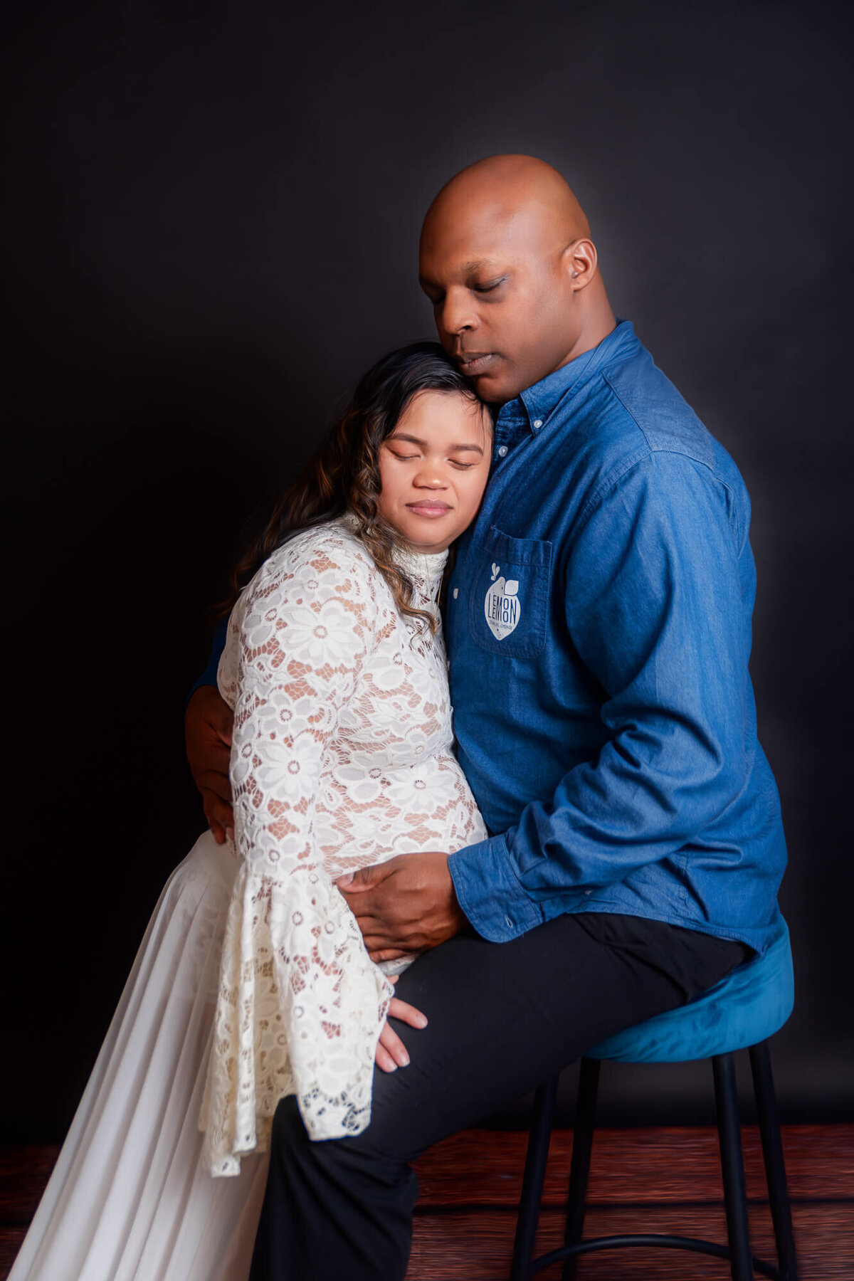 A happy couple poses together, with the woman showing off her baby bump, capturing a joyful moment of their pregnancy journey.