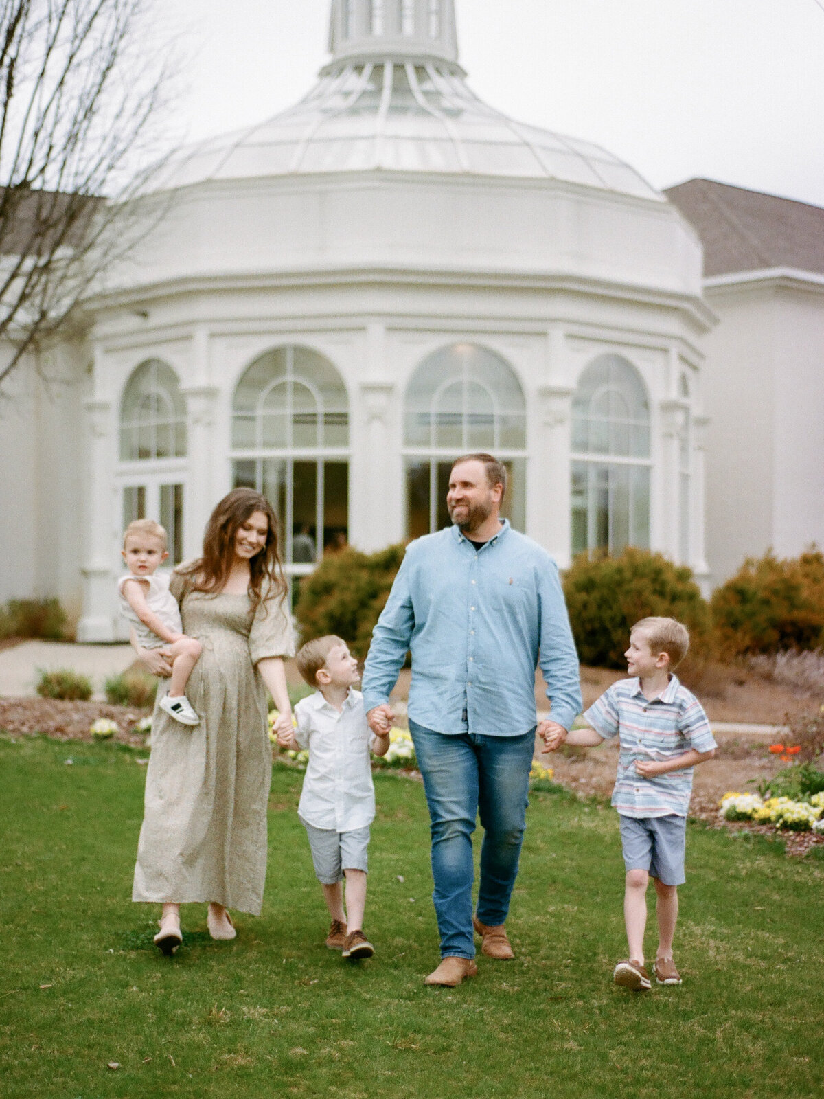 family of five in front of huntsville botanical garden conservatory at portrait session by fauna & film