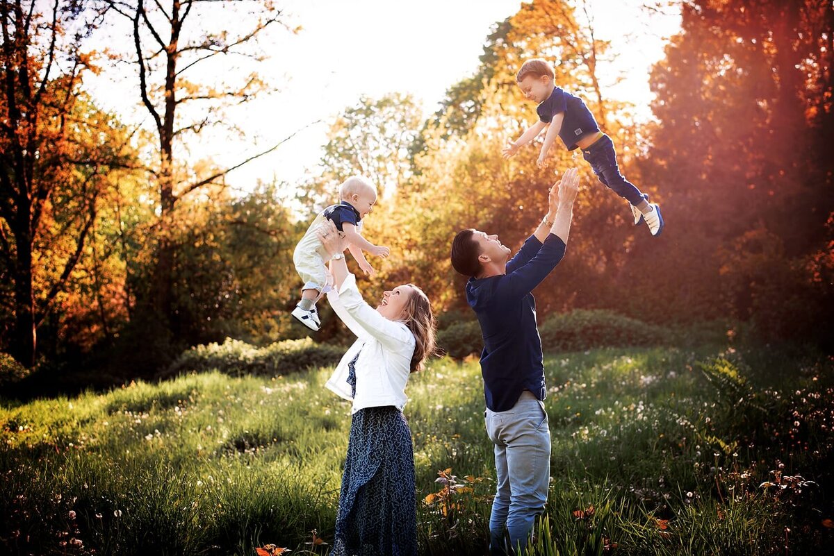Mother and father tossing sons in the air and laughing