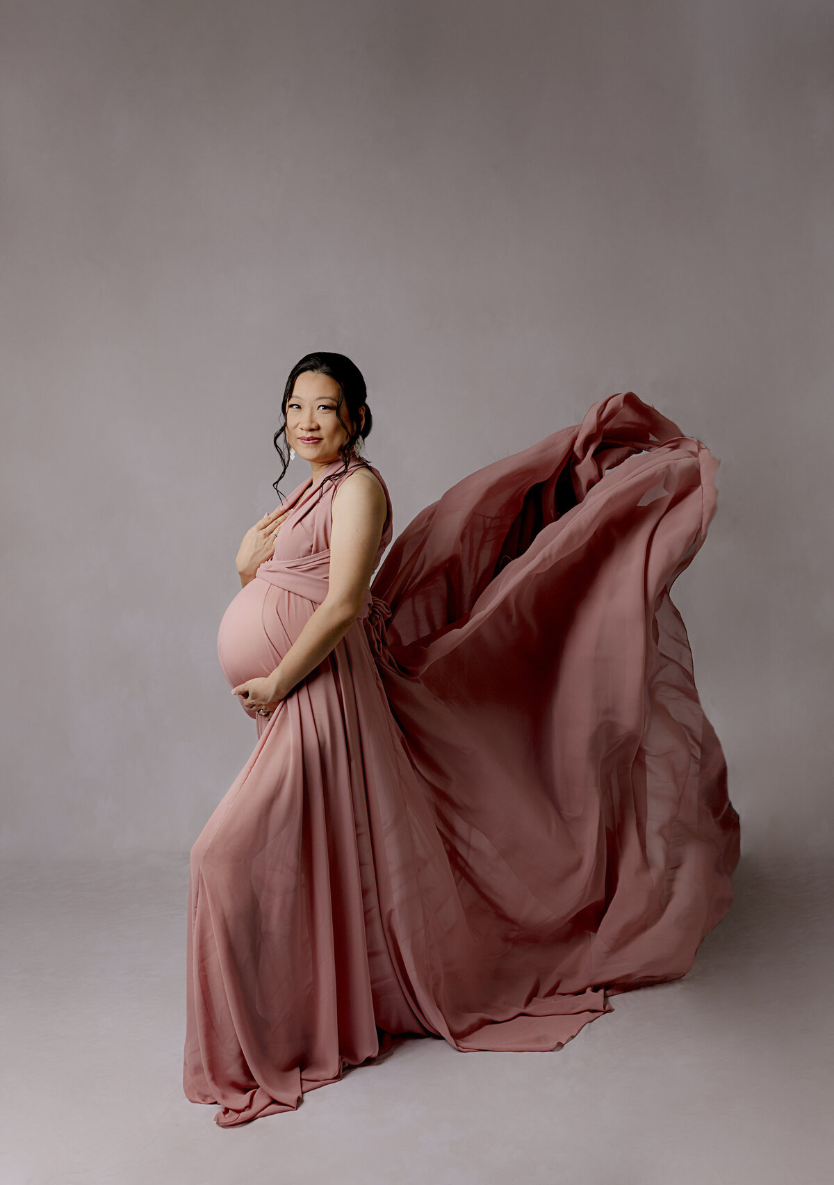 mother in pink dress holding pregnant stomach