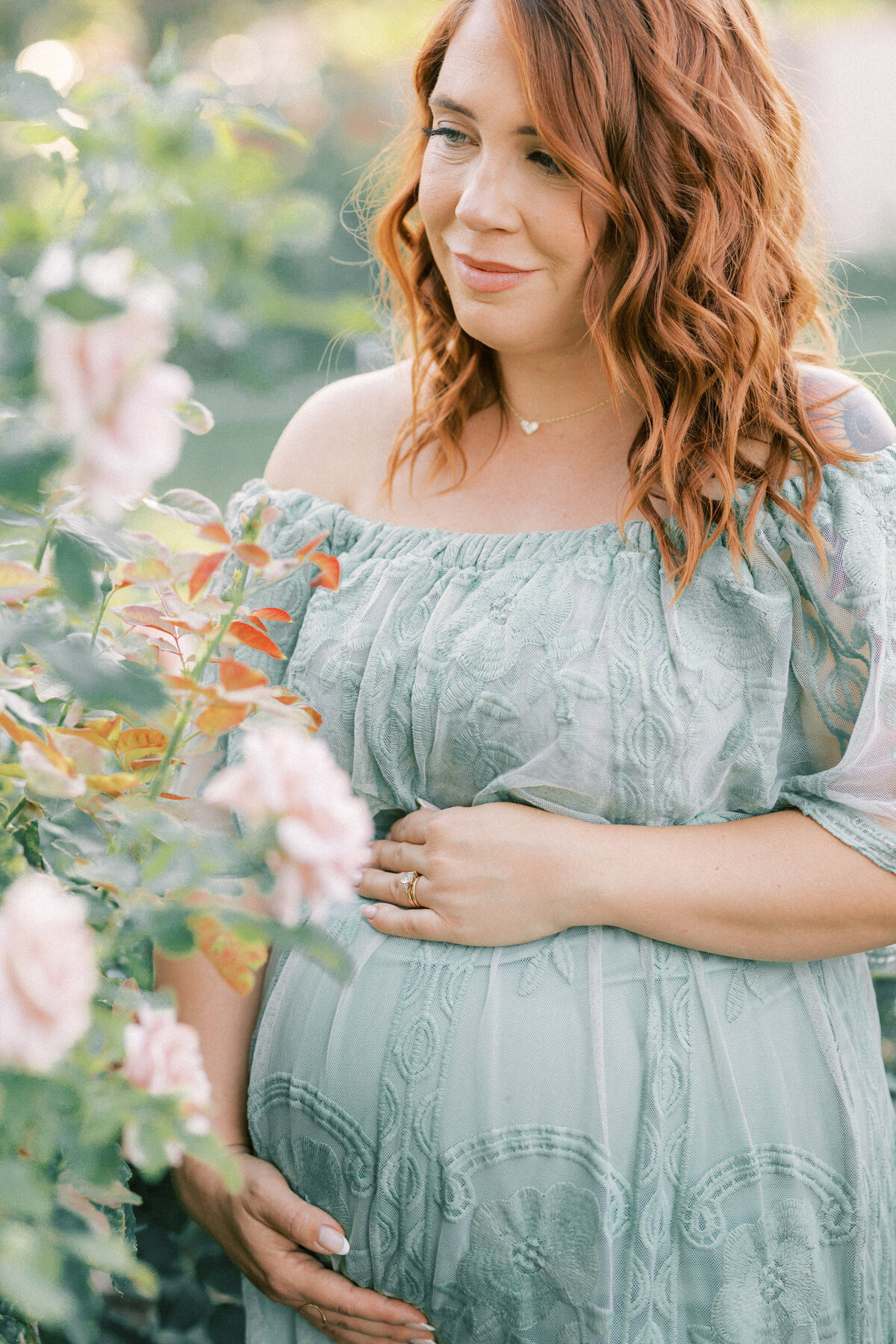 pregnant mom in green dress surrounded by roses