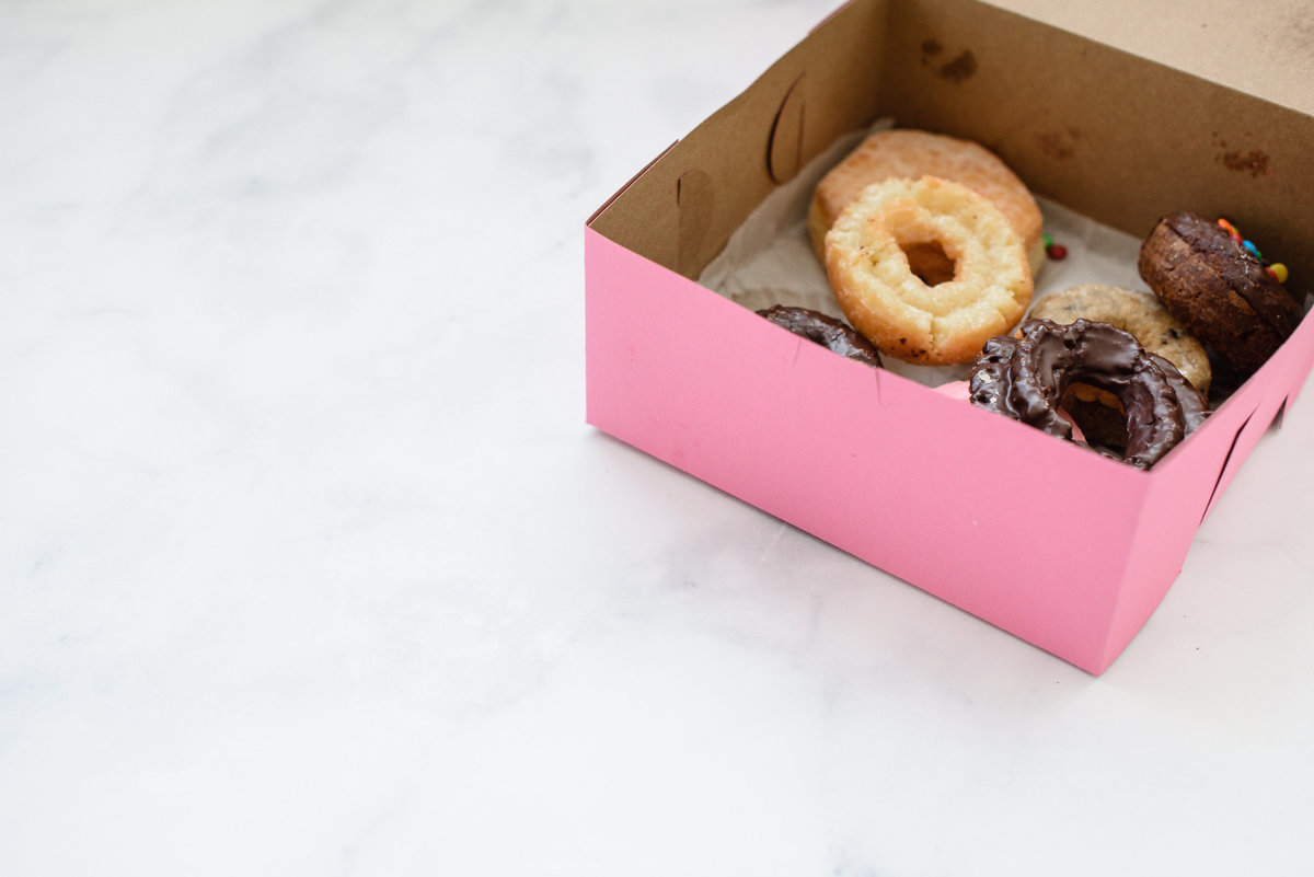A denver commercial photographer takes a picture of a pink box of donuts for a branding photography session and brand photos.