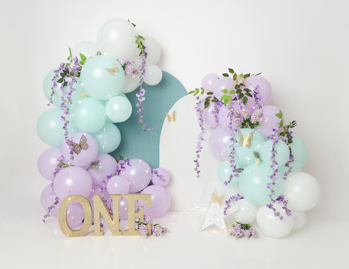 Capture unforgettable moments with our cake smash photography in Rochester, NY. Featuring beautiful purple and blue balloons paired with lilacs for a stunning backdrop.