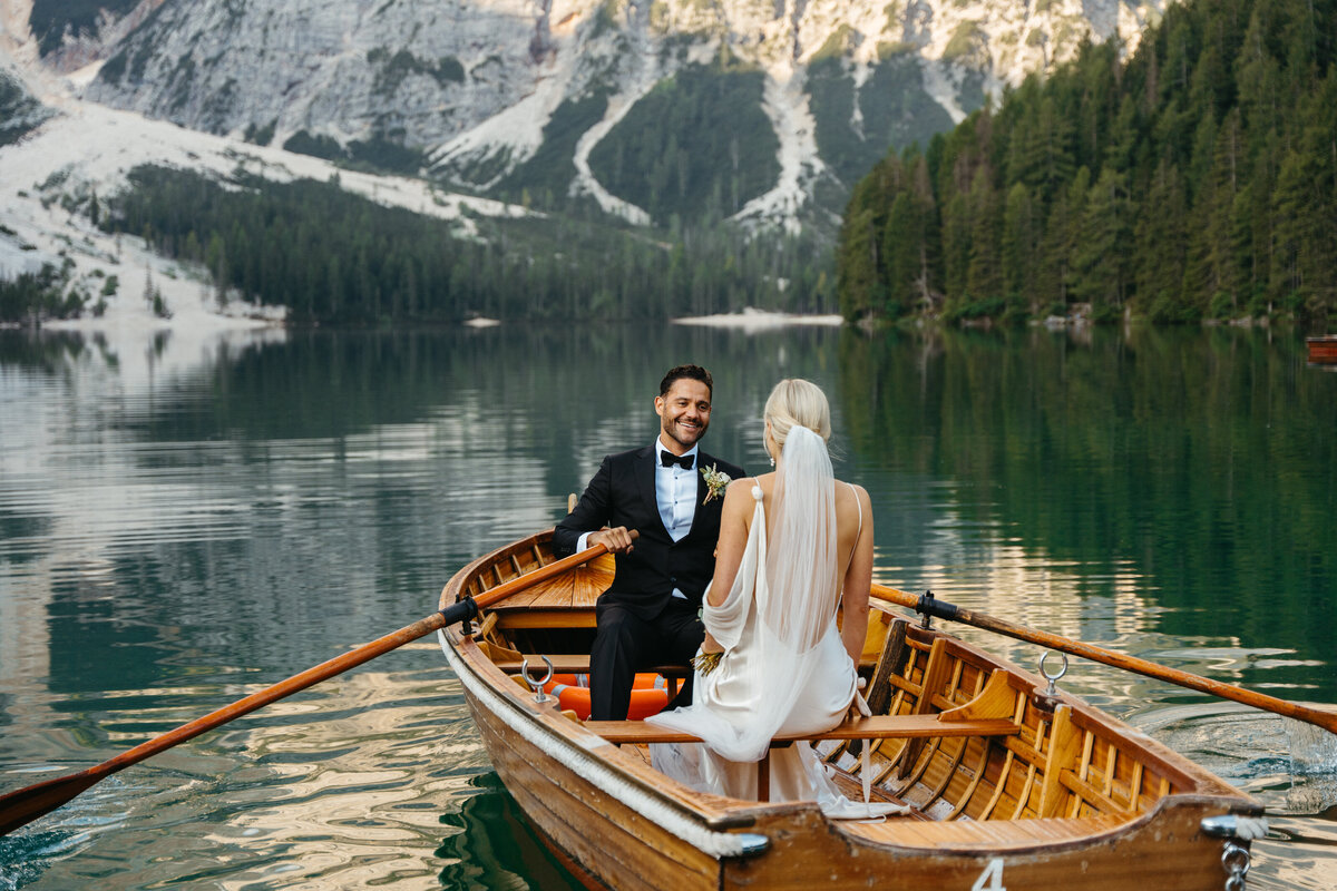 Bride and groom rowing wooden boat at Lago di Braies