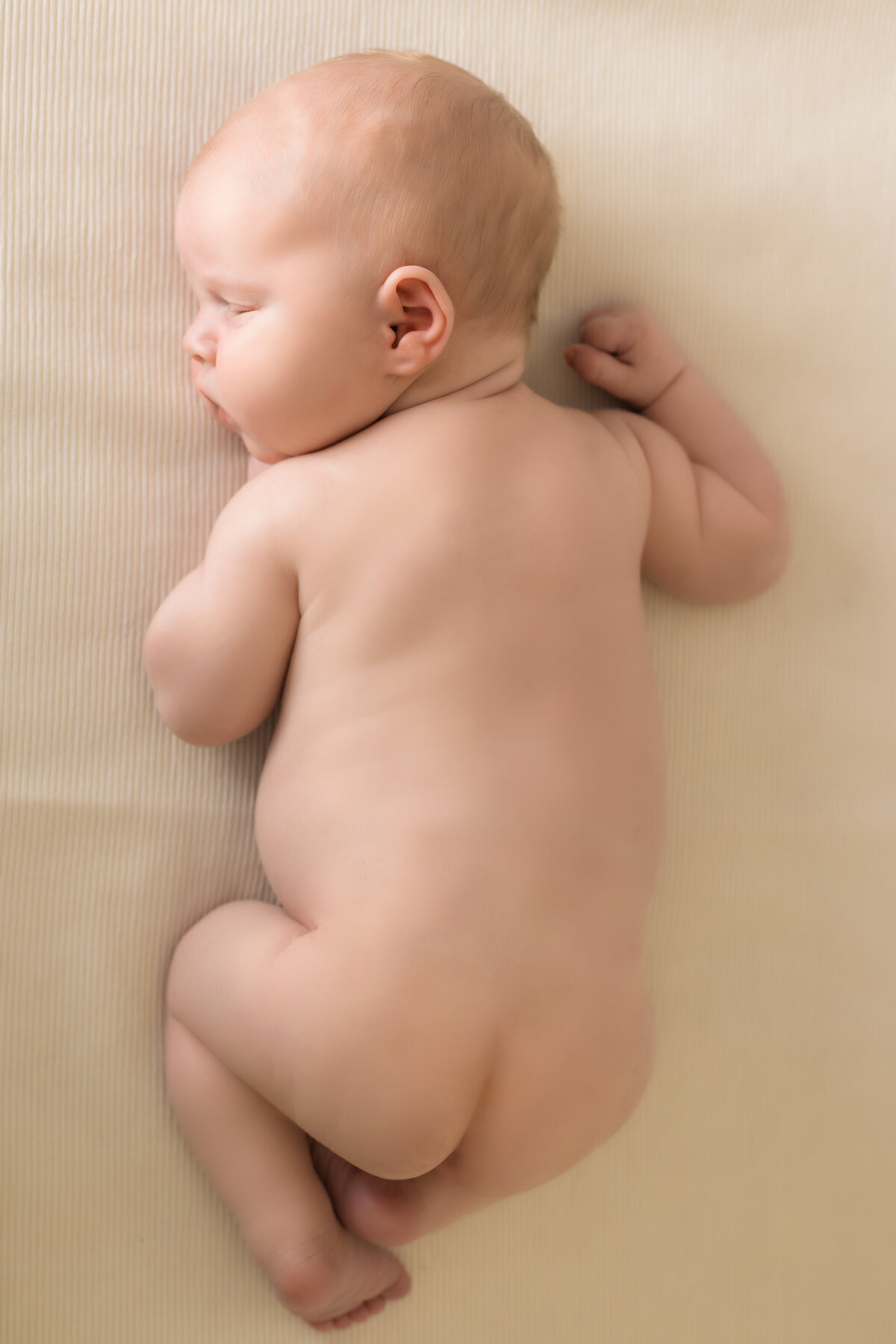 Newborn Photographer, a baby lays on the bed asleep