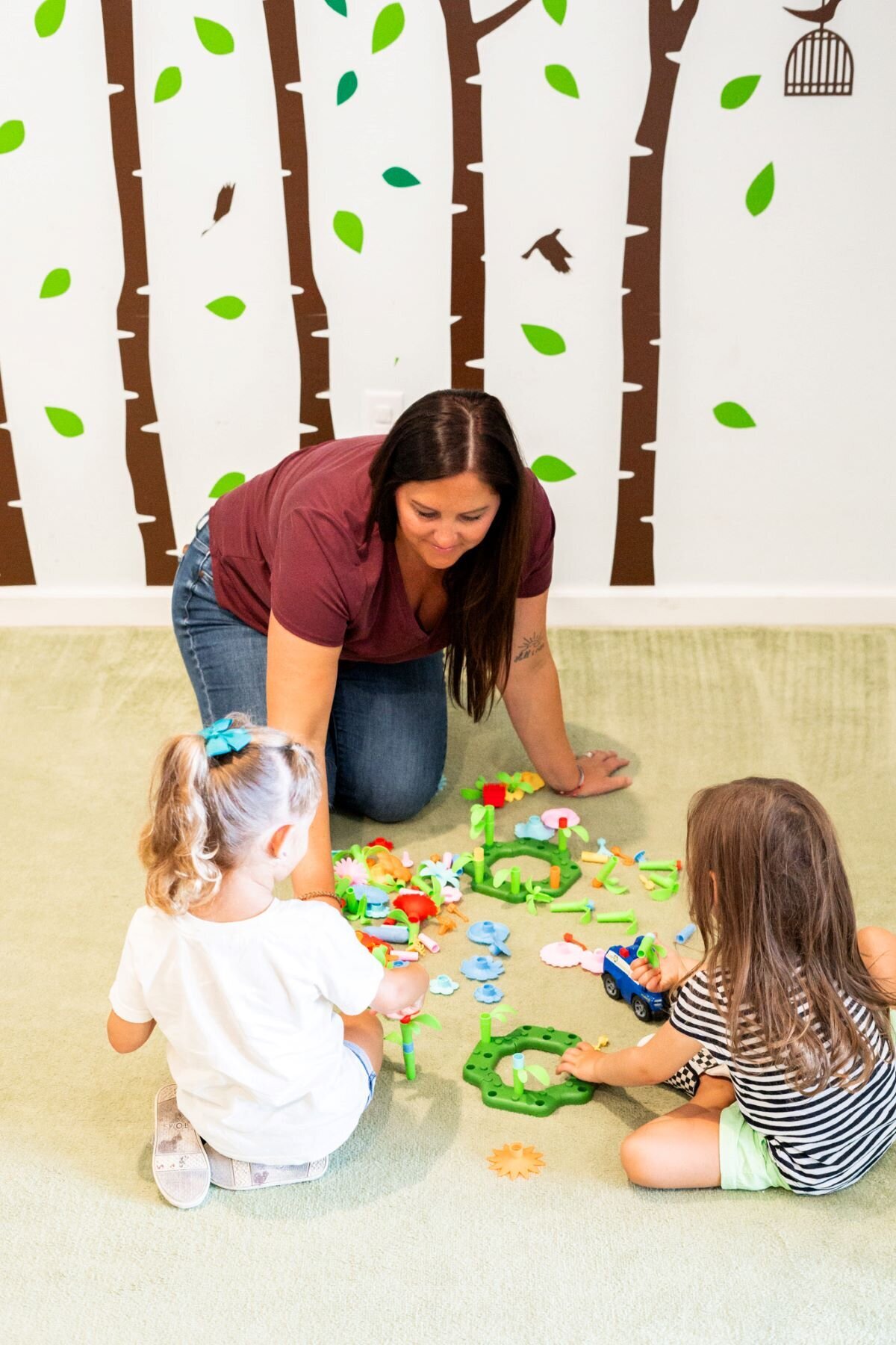 Ms. Brandi playing with two young students in the classroom at The Nest, a preschool and learning center in Surf City, North Carolina