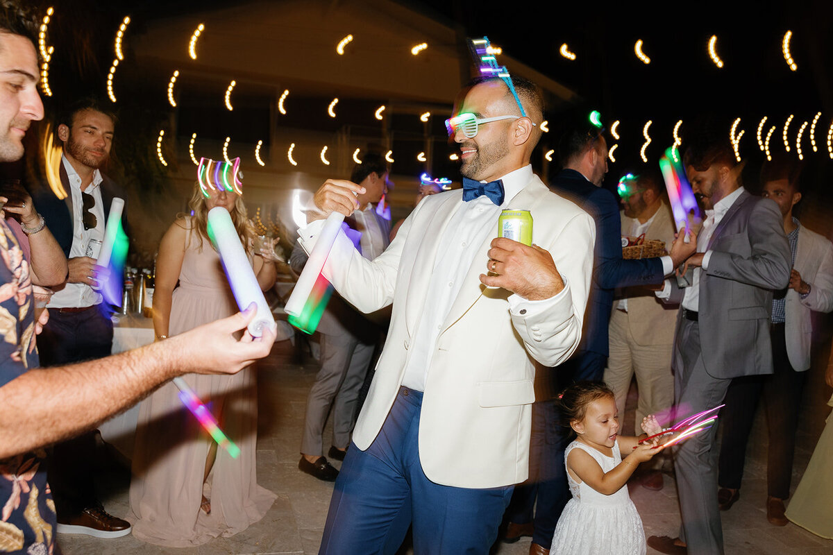 Rafael enjoys the wedding reception party under string lights, celebrating with glow sticks at La Siesta Marina.