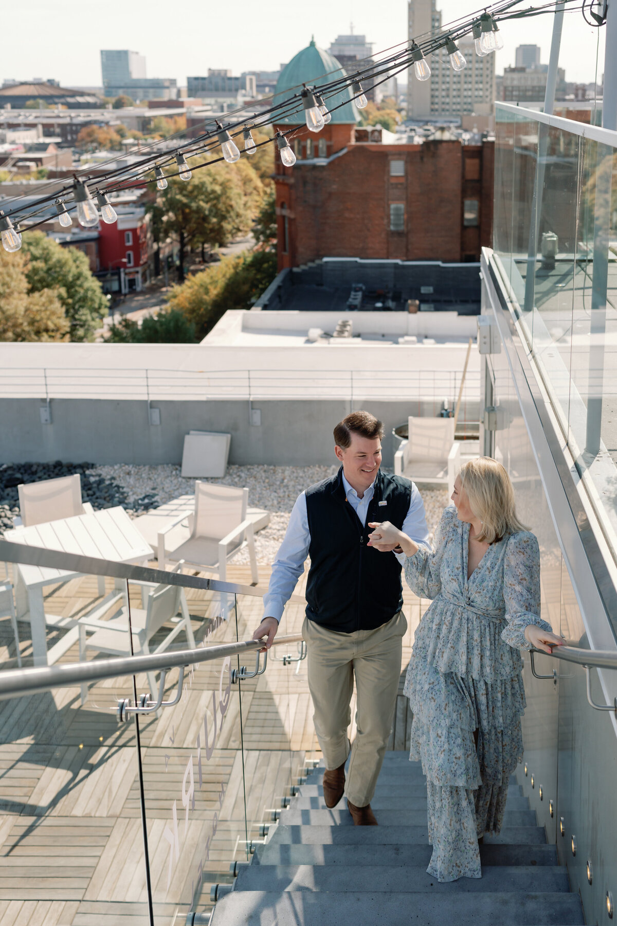 Quirk Hotel RVA Engagement Session in Richmond, VA | Engagement and Wedding Photographer in Richmond | couple walking up the stairs hand in hand on the rooftop of the Quirk Hotel in Richmond