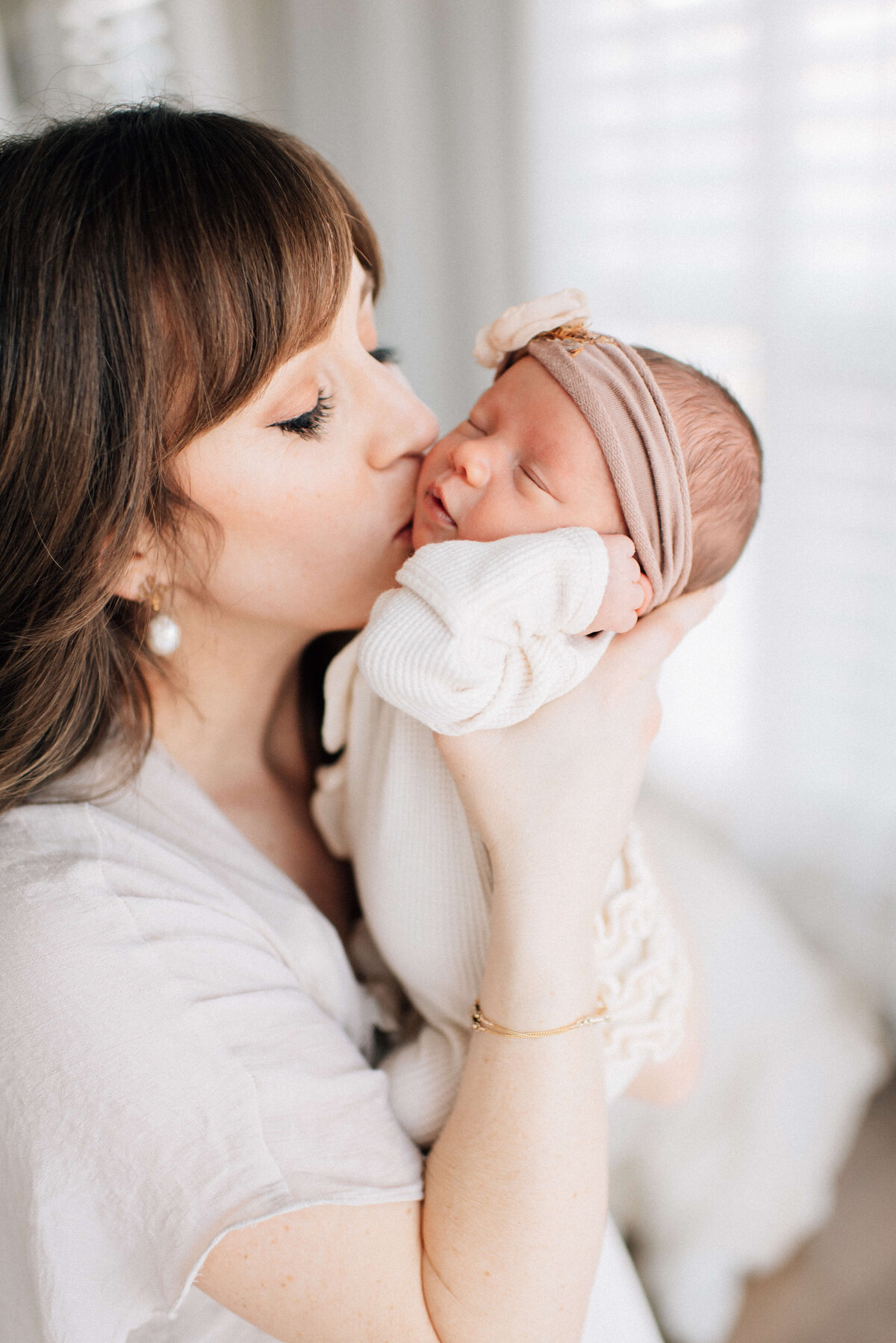 mother lifting up her newborn baby to kiss her