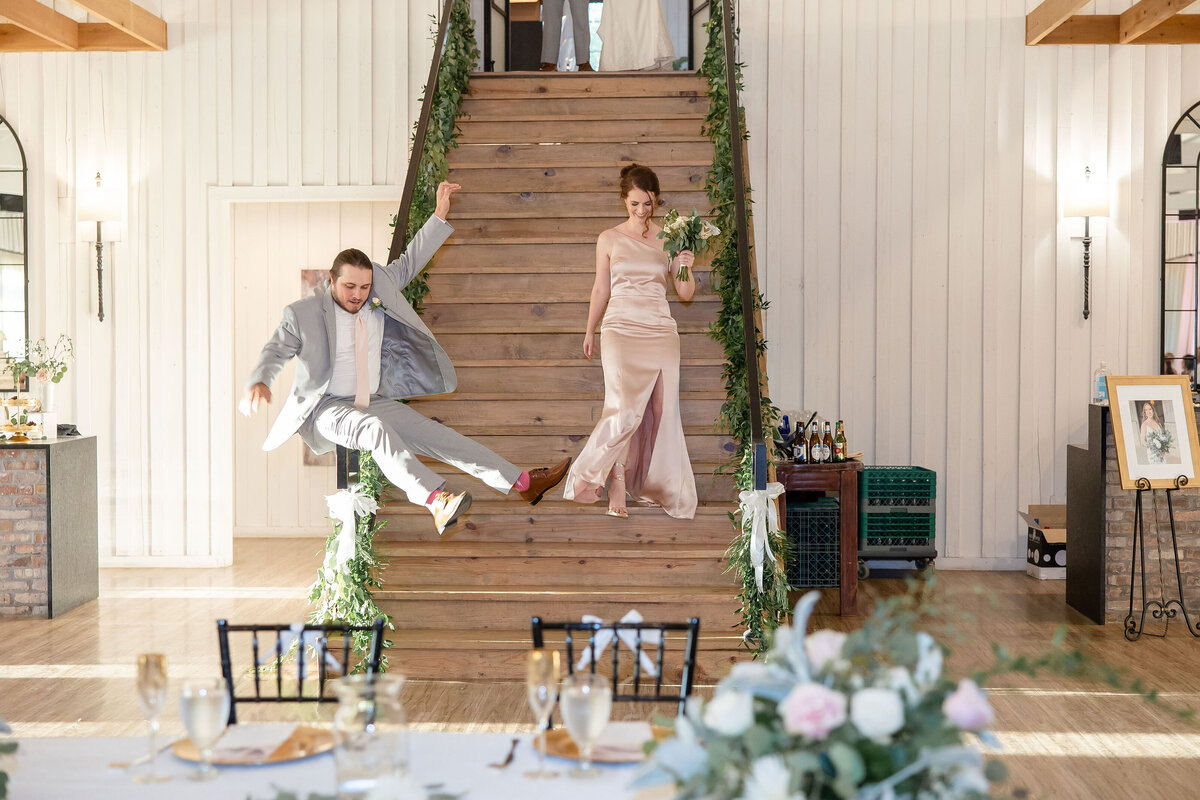 groomsman slides down stair rail as announced at Milestone New Braunfels wedding reception