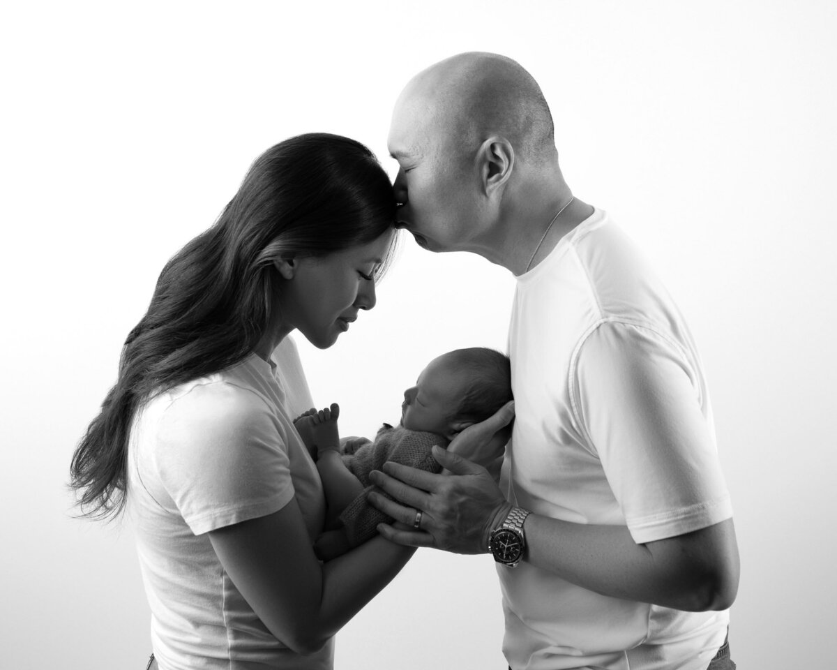 Black white couple kissing with newborn Lakeway family portrait photographer
