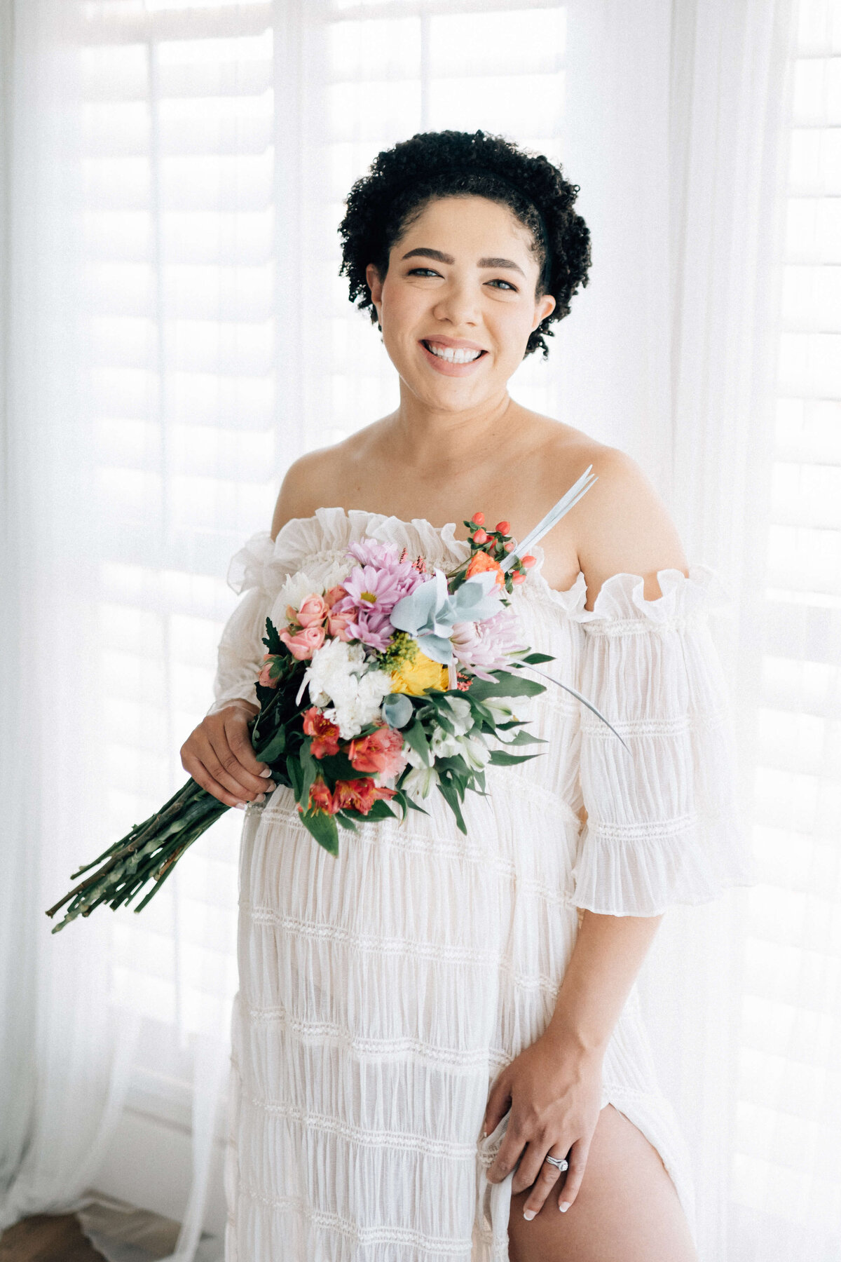 maternity woman looking at Denver photographer while holding flowers