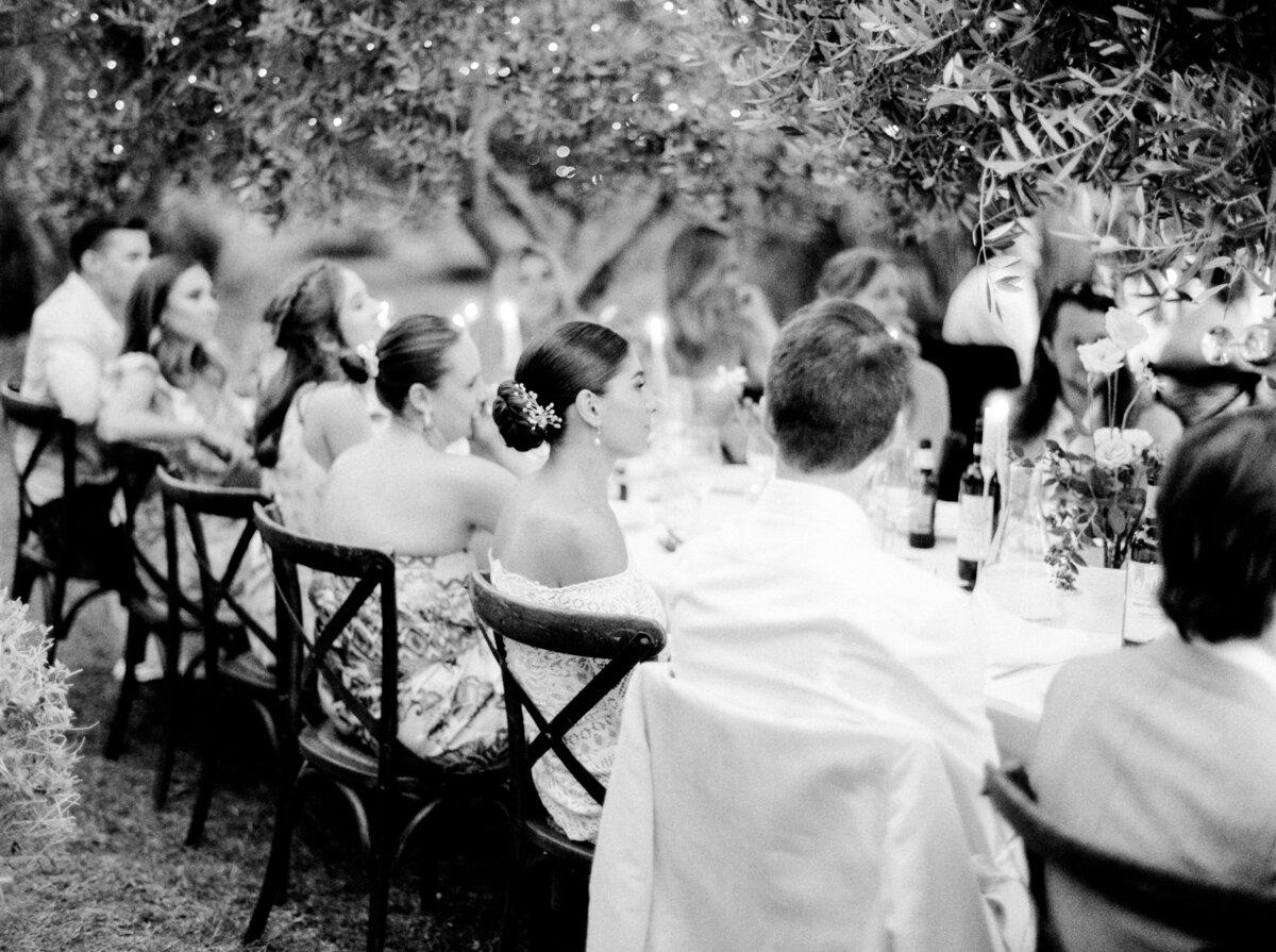 Black and white film photograph of wedding reception table filled with guests