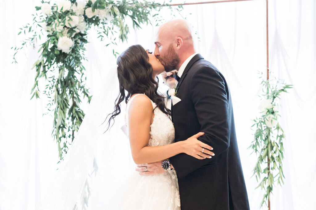 Modern wedding ceremony arch bride and groom kissing