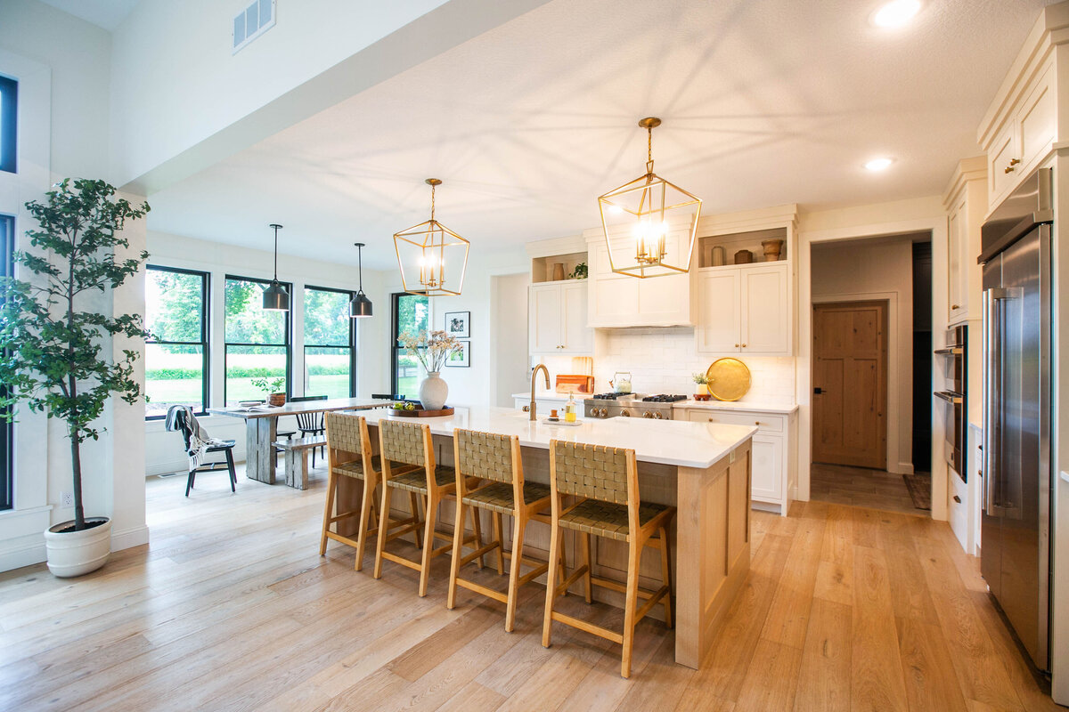 Open kitchen with white cabinets, large island, and quartz countertops in an Otsego custom home
