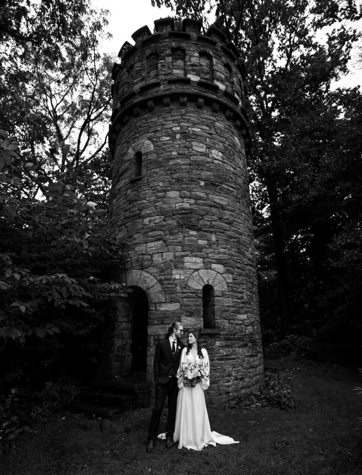 Bride and groom stand in front of castle at Duke Sculpture Garden at Dixon Mansion