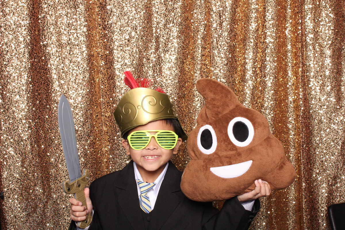 Young boy poses with a prop knife and poop pillow in a photo booth