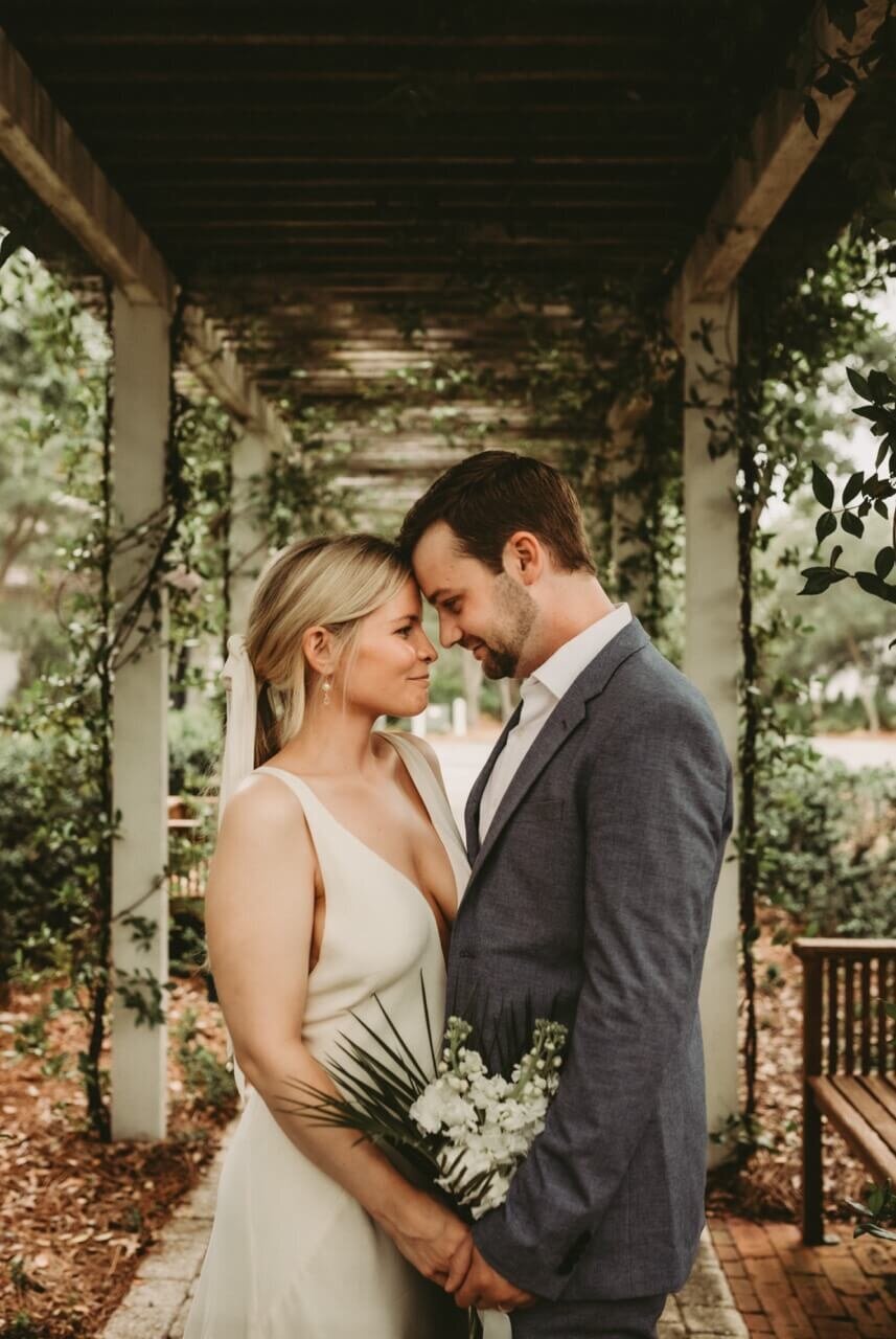 young bride & groom press forehead to forehead under garden arbor in rosemary beach elopement