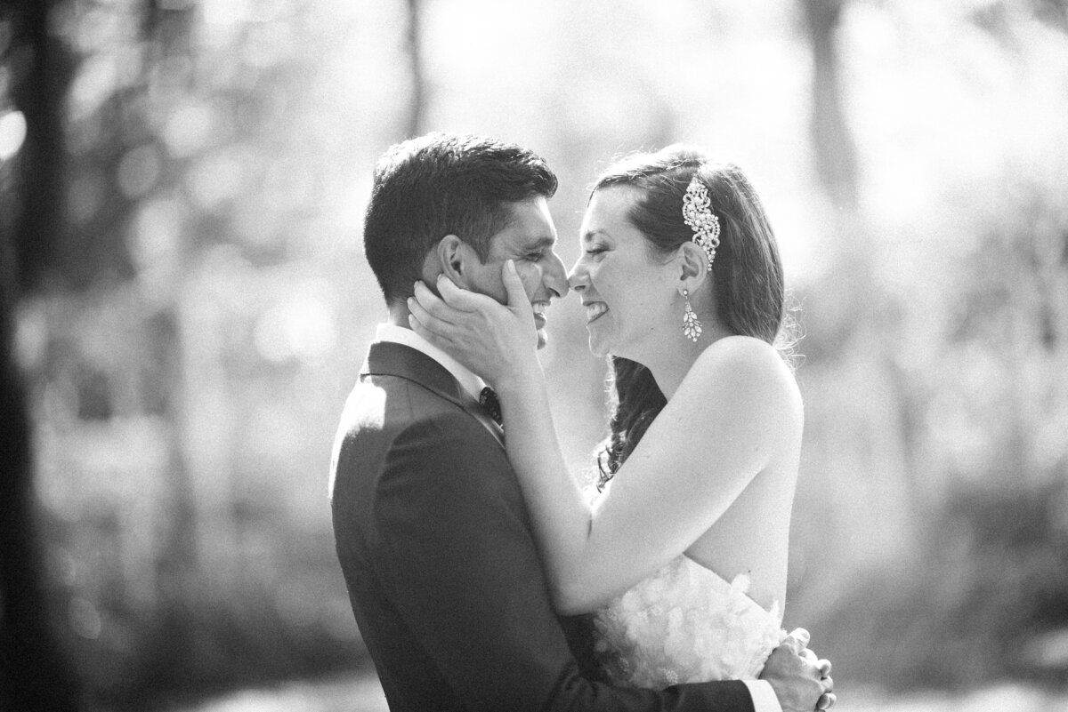 A bride with her hands on her grooms face as she is touching her nose to his.