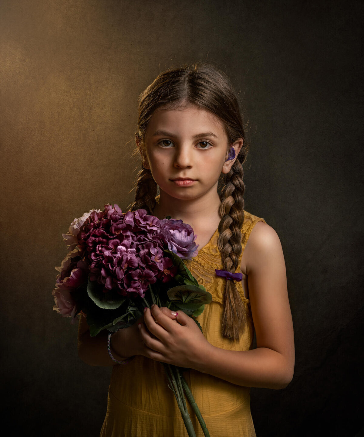 A little girl in a yellow dress with braids in her hair holding purple flowers