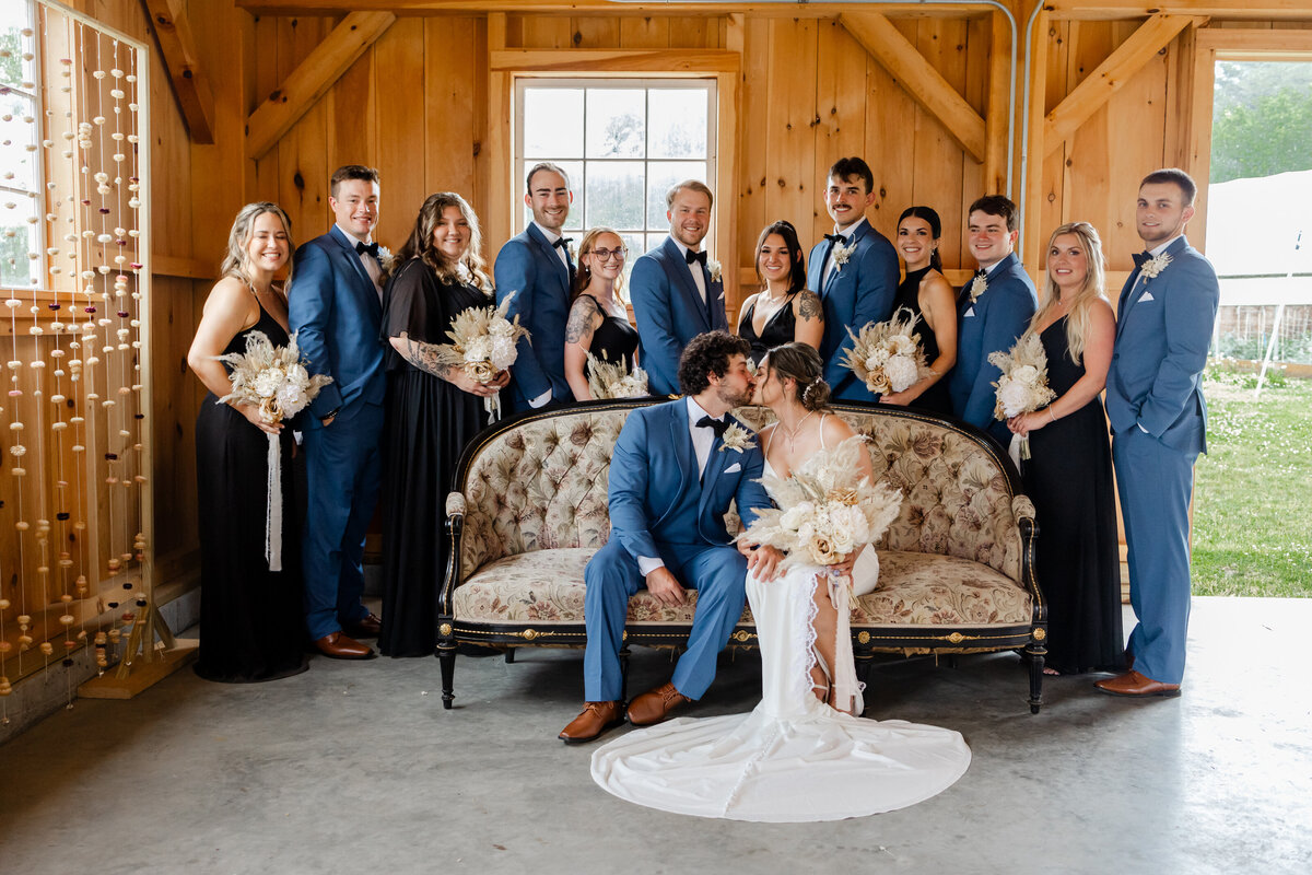 Bride and groom with their wedding party sharing a kiss