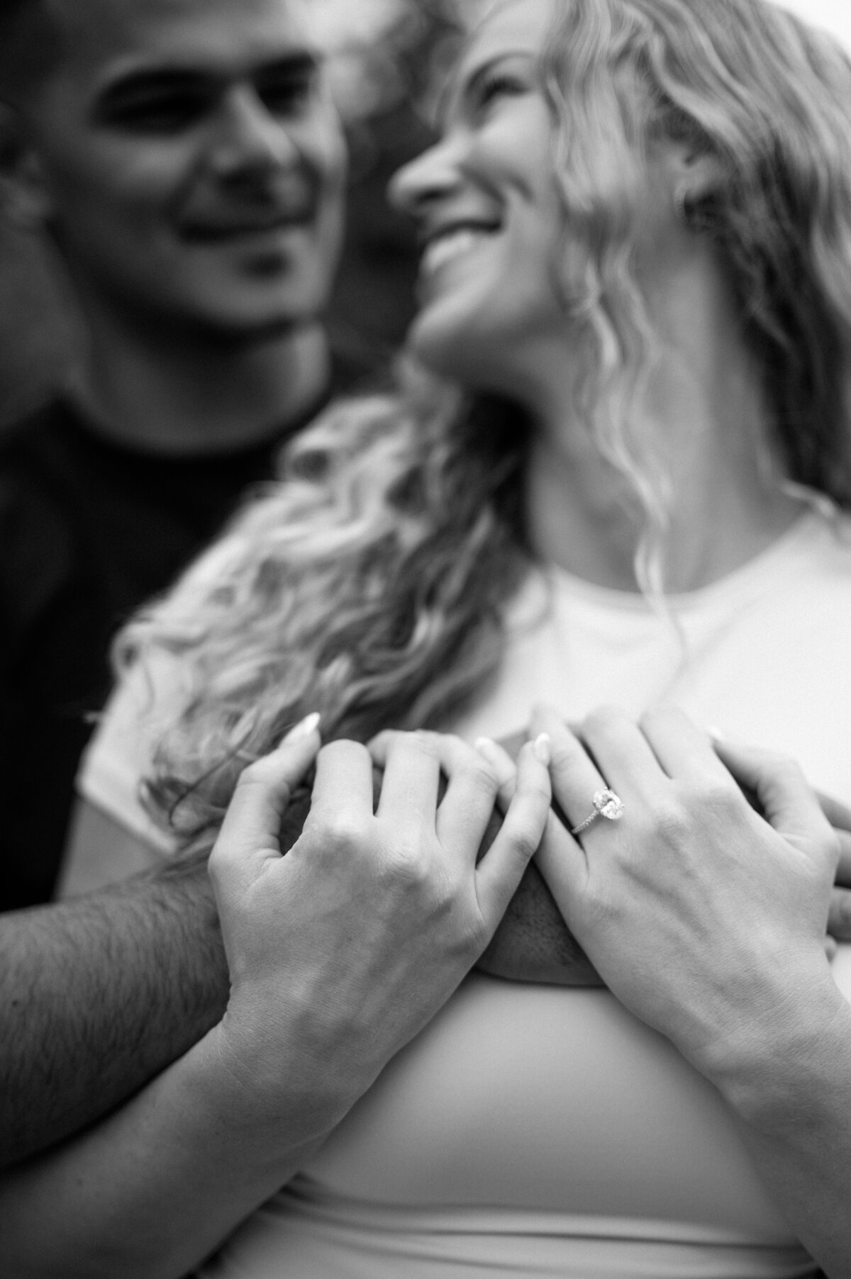 Close-up black and white photo of hands and engagement ring at Emerald Lake.