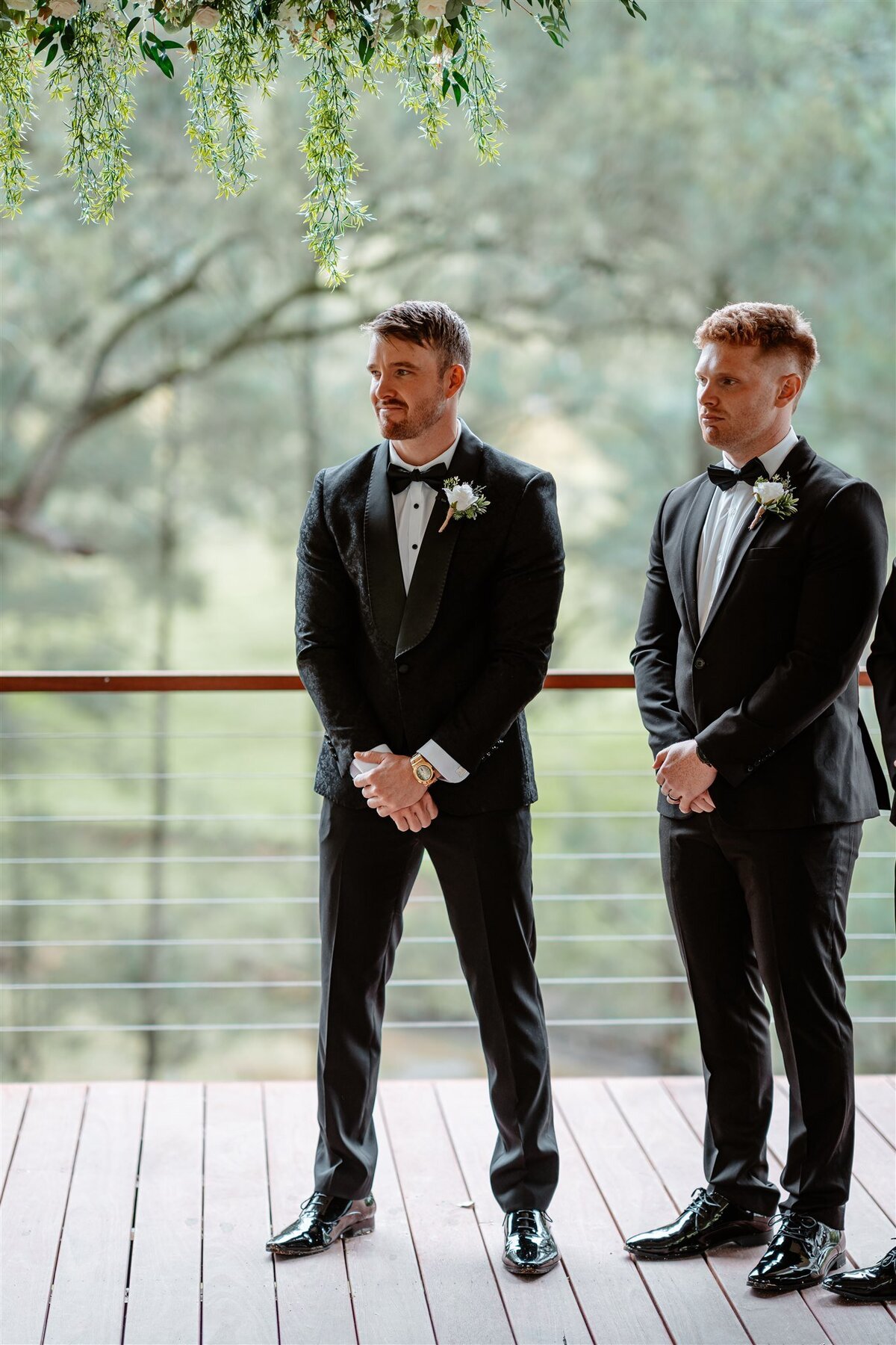 The groom stands with an emotional smile, eagerly awaiting his bride.