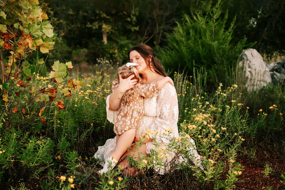 Springfield MO maternity picture of pregnant mom hugging toddler in yellow flower field