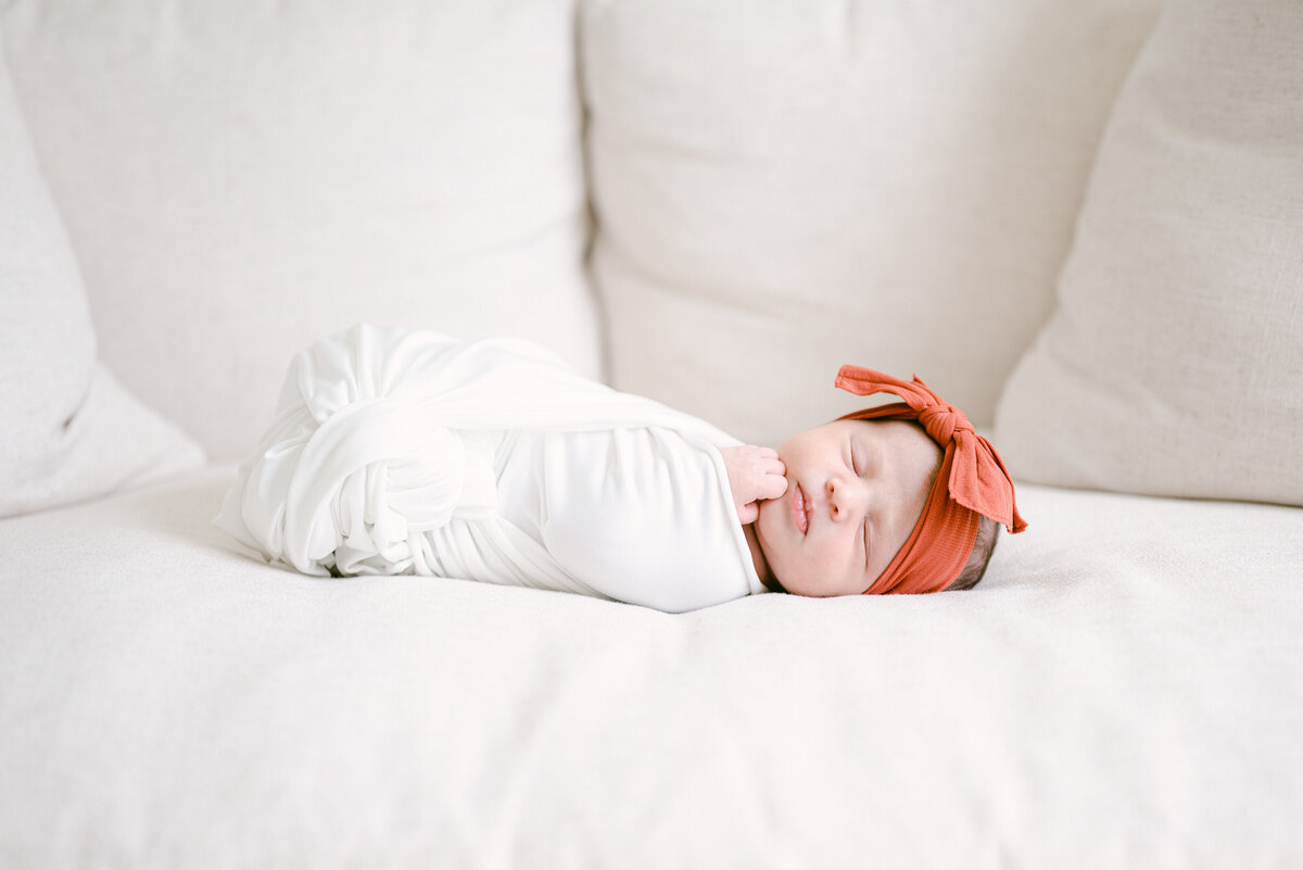 A baby with a bow swaddled is sleeping